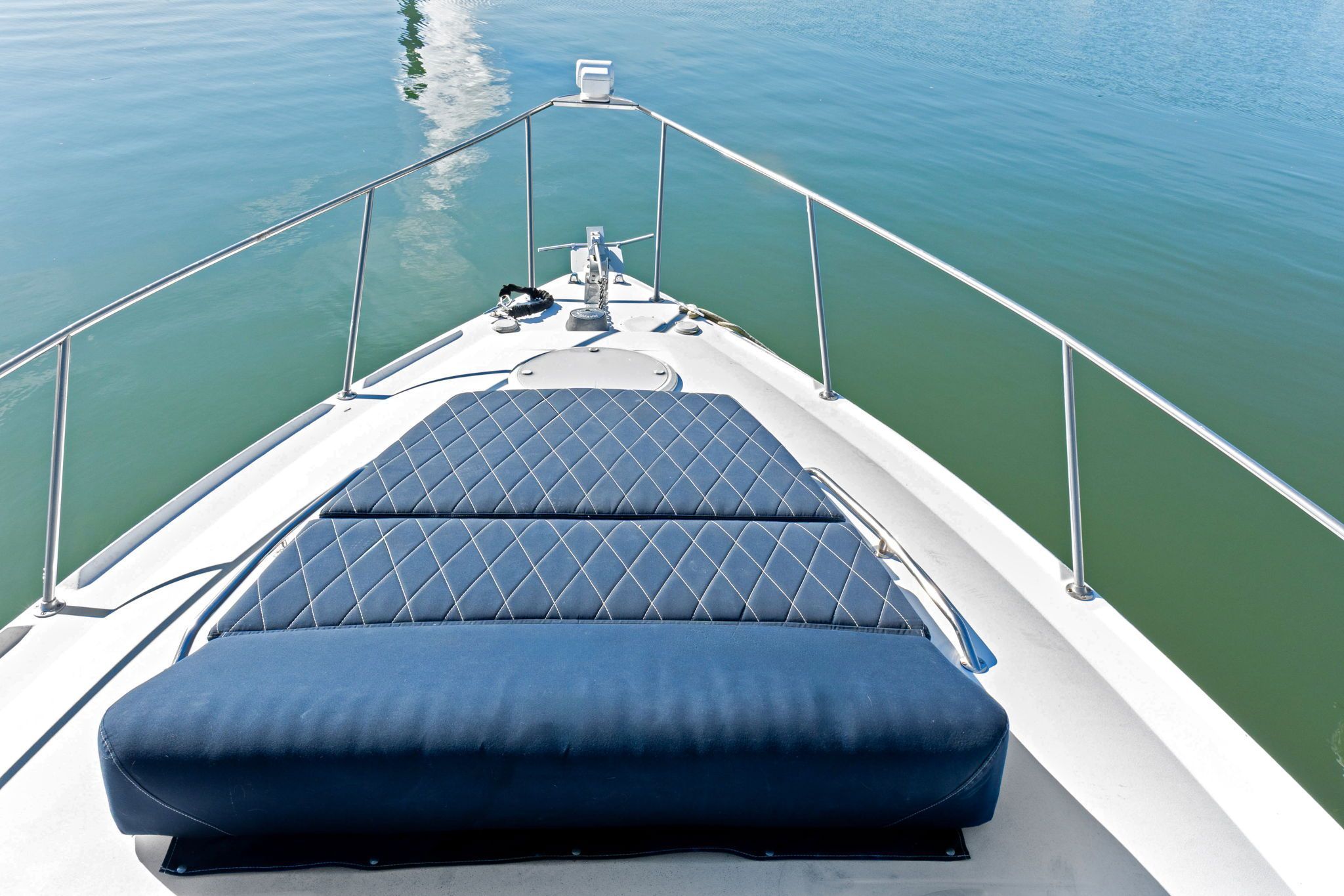 The bow of a 2007 Larson Cabrio 330 with blue upholstery on calm water.