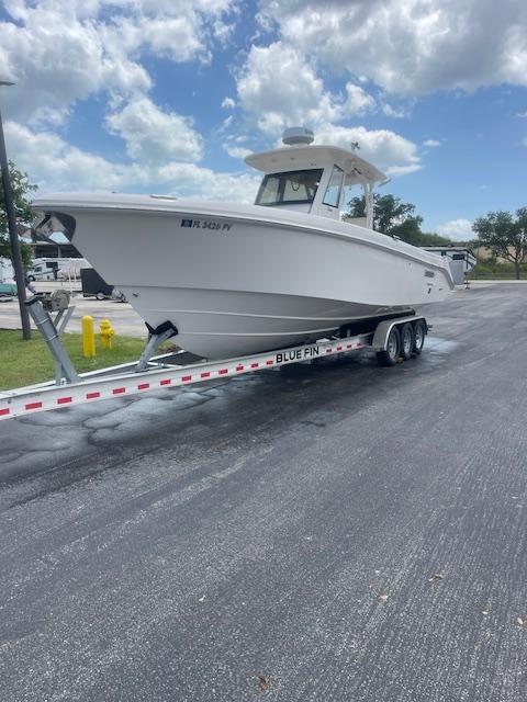 2014 Everglades 325 Center Console boat on trailer, parked on asphalt under cloudy sky.