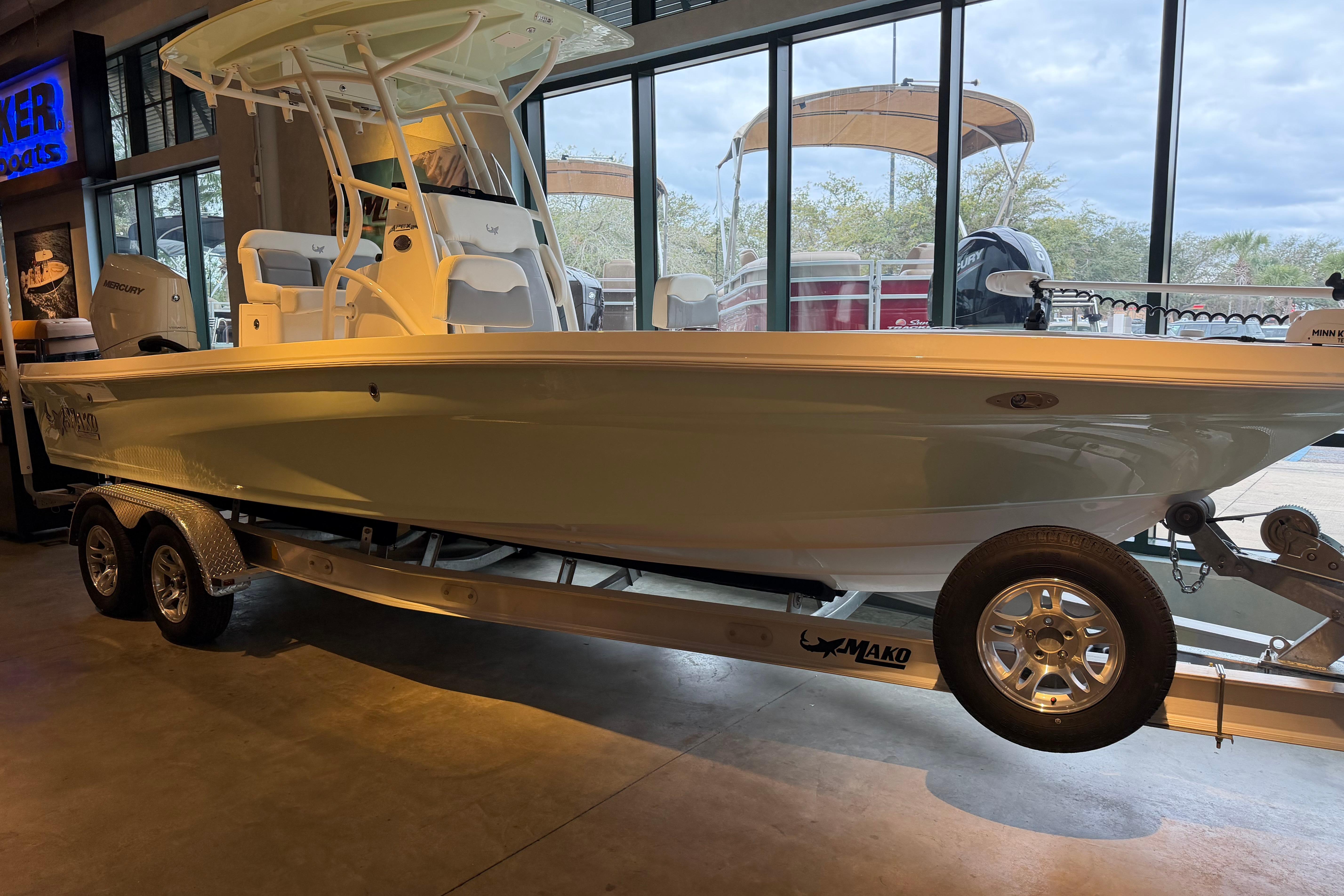 2026 Mako 24 APEX boat on trailer in showroom, side view.