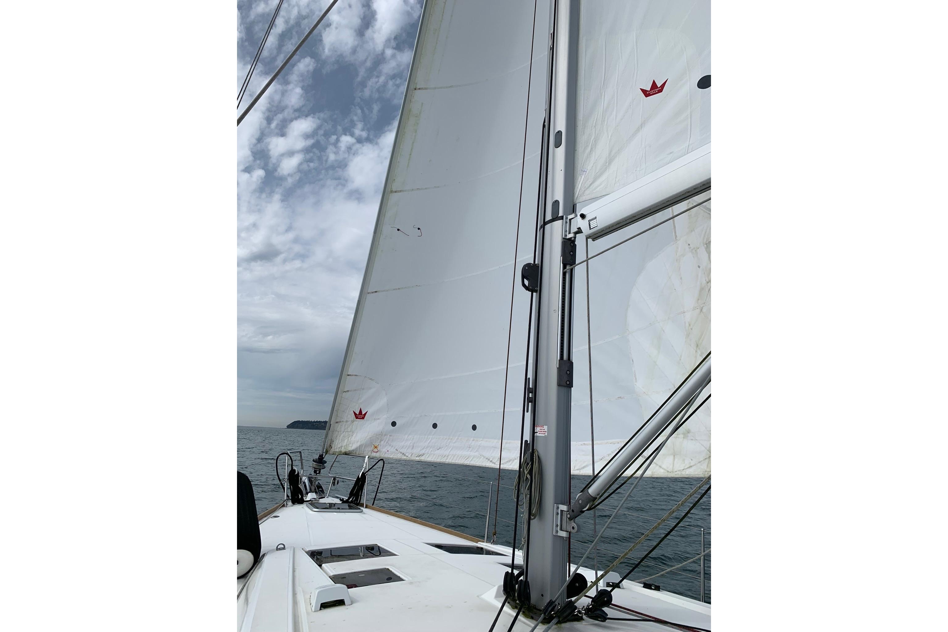 Sailing on a 2018 Beneteau Oceanis 45 with white sails against a cloudy sky.
