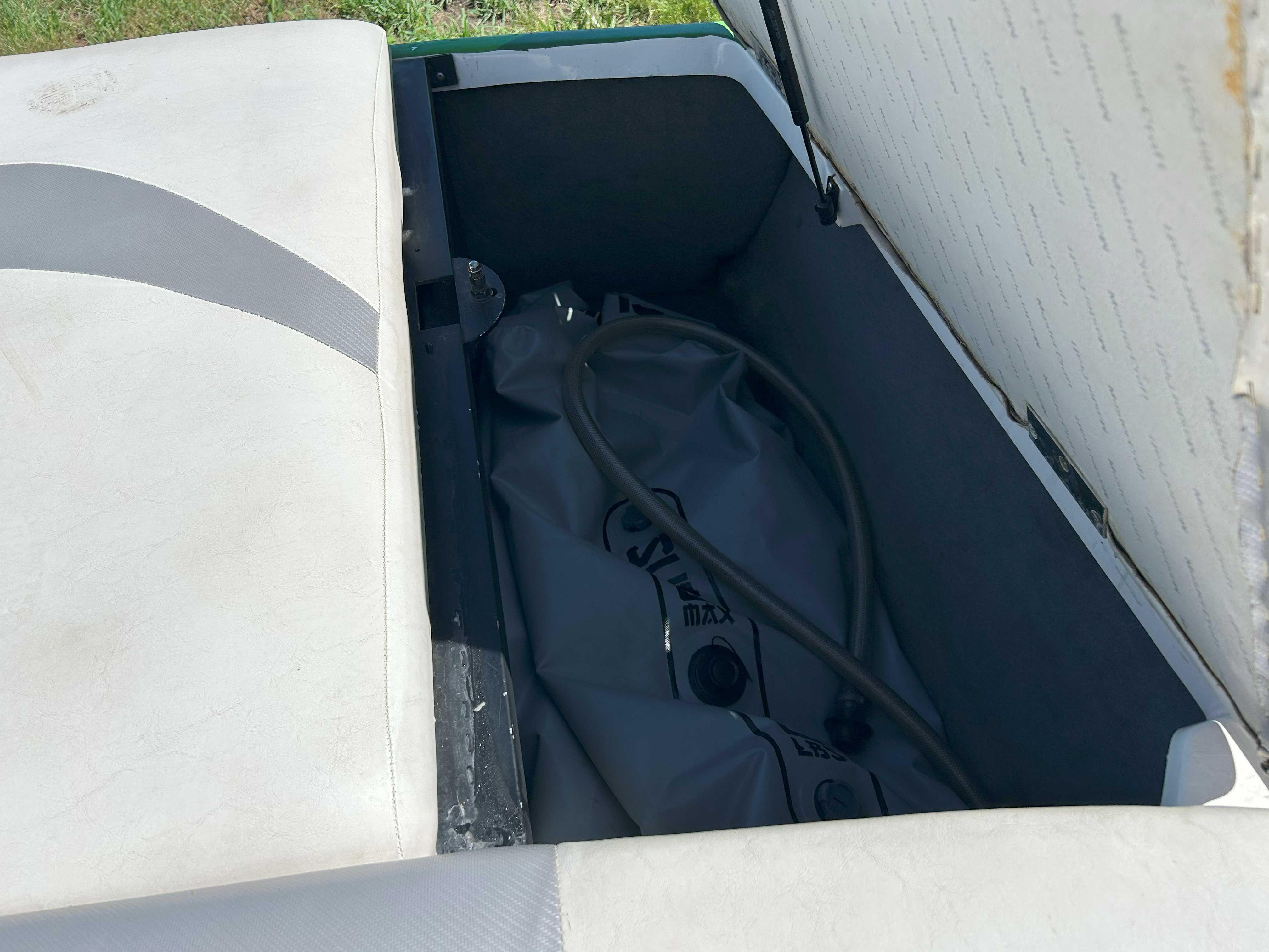 Open storage compartment in 2002 MasterCraft XStar boat with ballast bag inside.