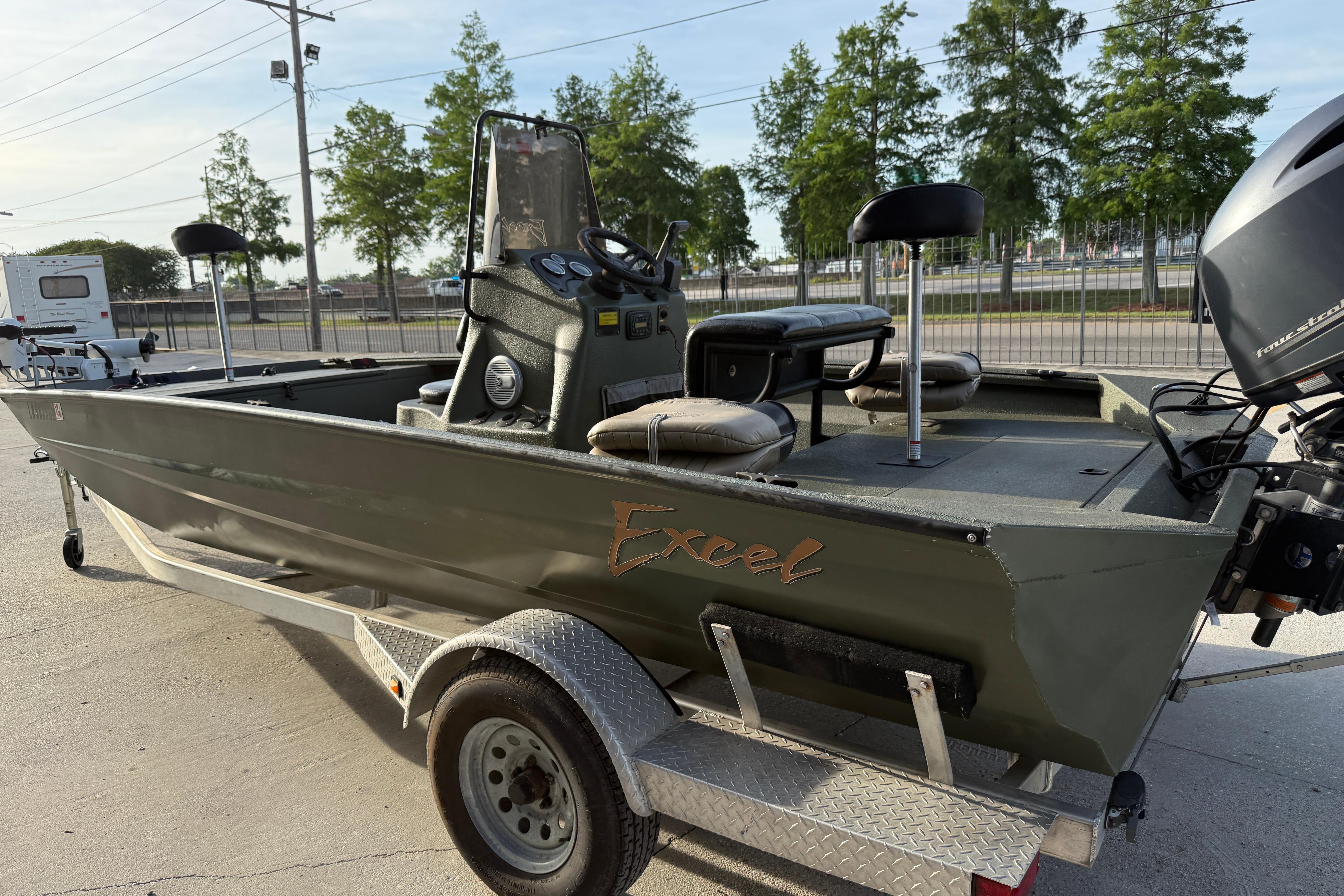 2014 Excel 203 Bay Pro boat on trailer, featuring seating and motor, parked outdoors.
