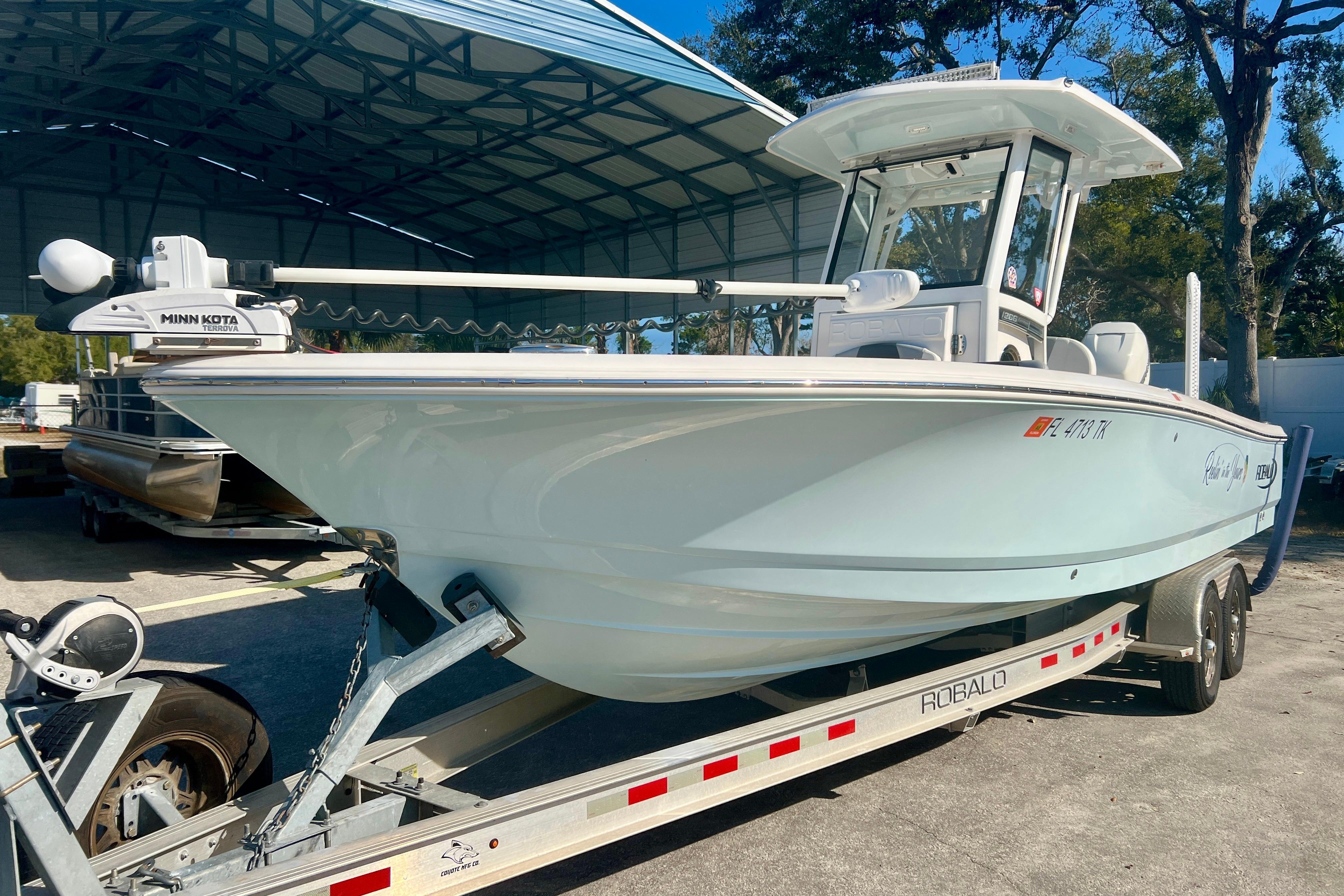 2023 Robalo 266 Cayman boat on trailer under shelter, featuring Minn Kota Terrova motor.