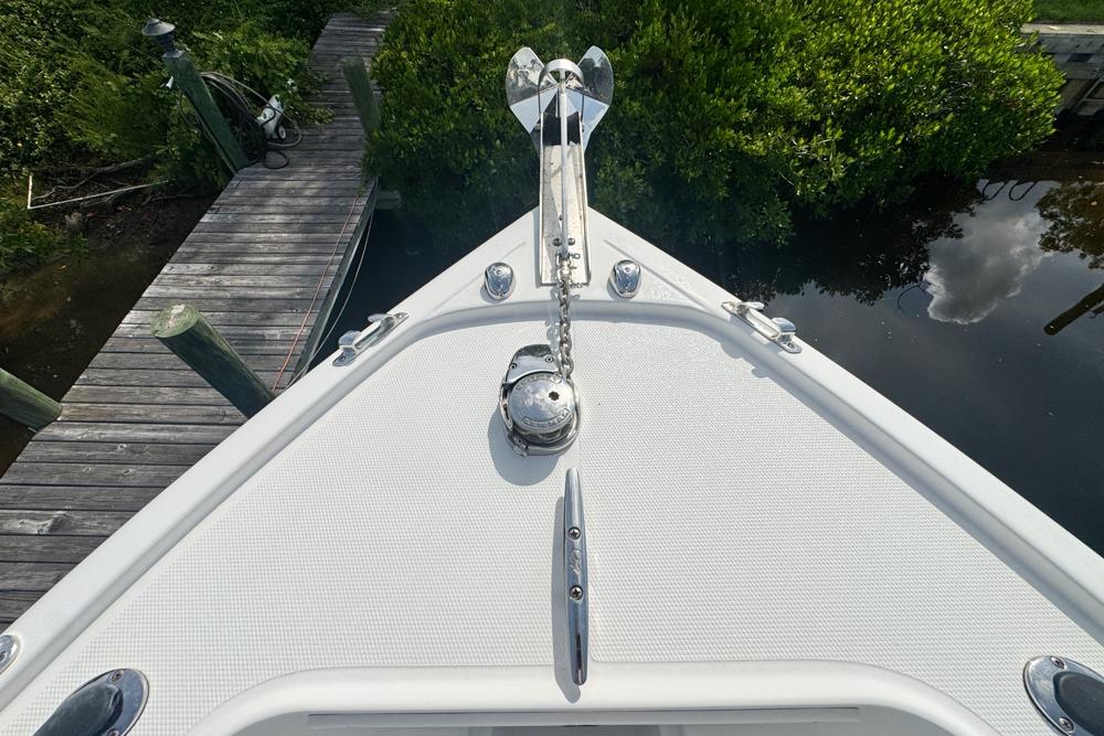 Bow of 2018 Mako 284 Center Console boat docked near lush greenery.