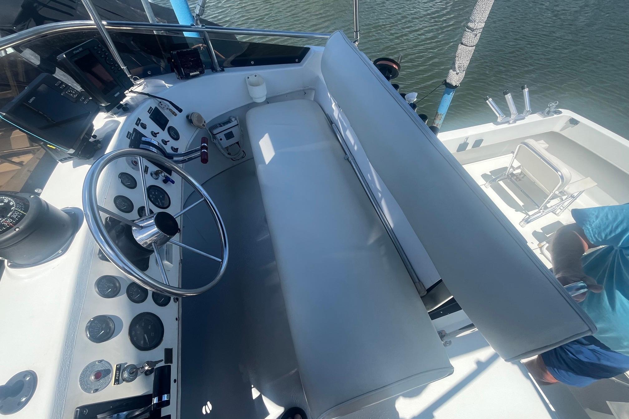 1988 Seafox 29 Flybridge helm with steering wheel, gauges, and seating, overlooking water.