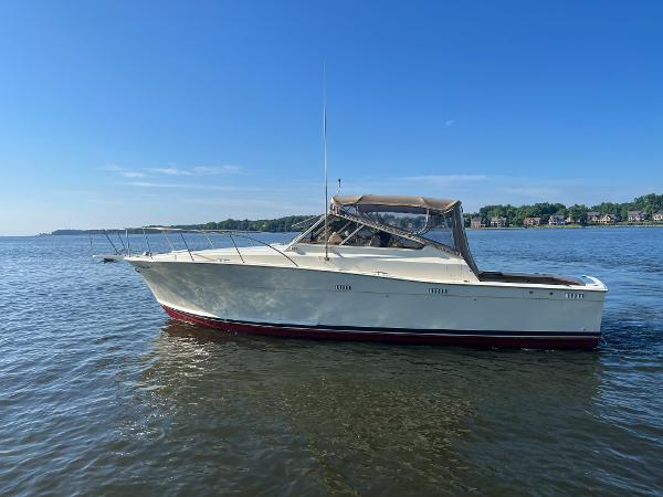 A white boat with a red underside floats on calm water under a blue sky.