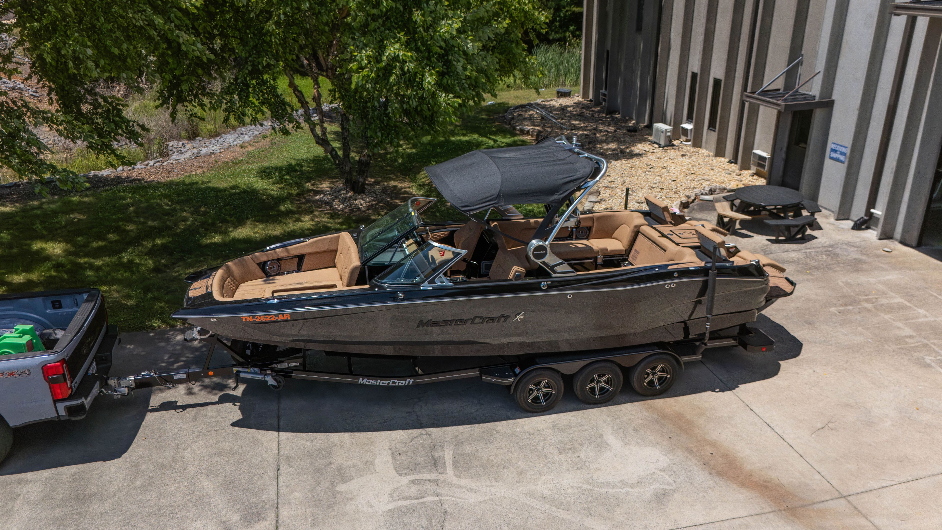A 2021 MasterCraft X26 on a trailer, ready for transport. It features a black canopy.