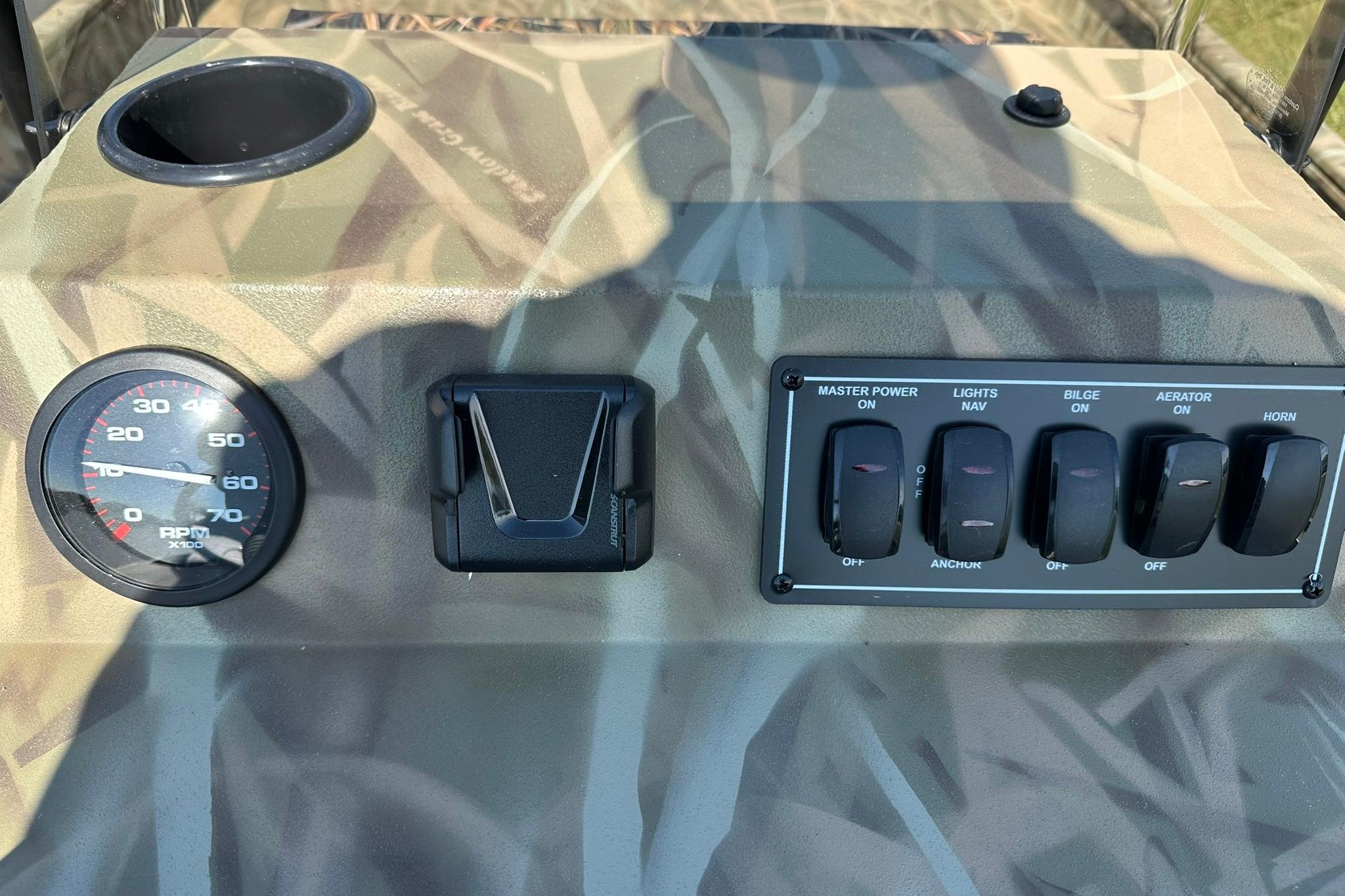 Control panel of 2026 Lowe Roughneck 2070CC boat with switches and RPM gauge.