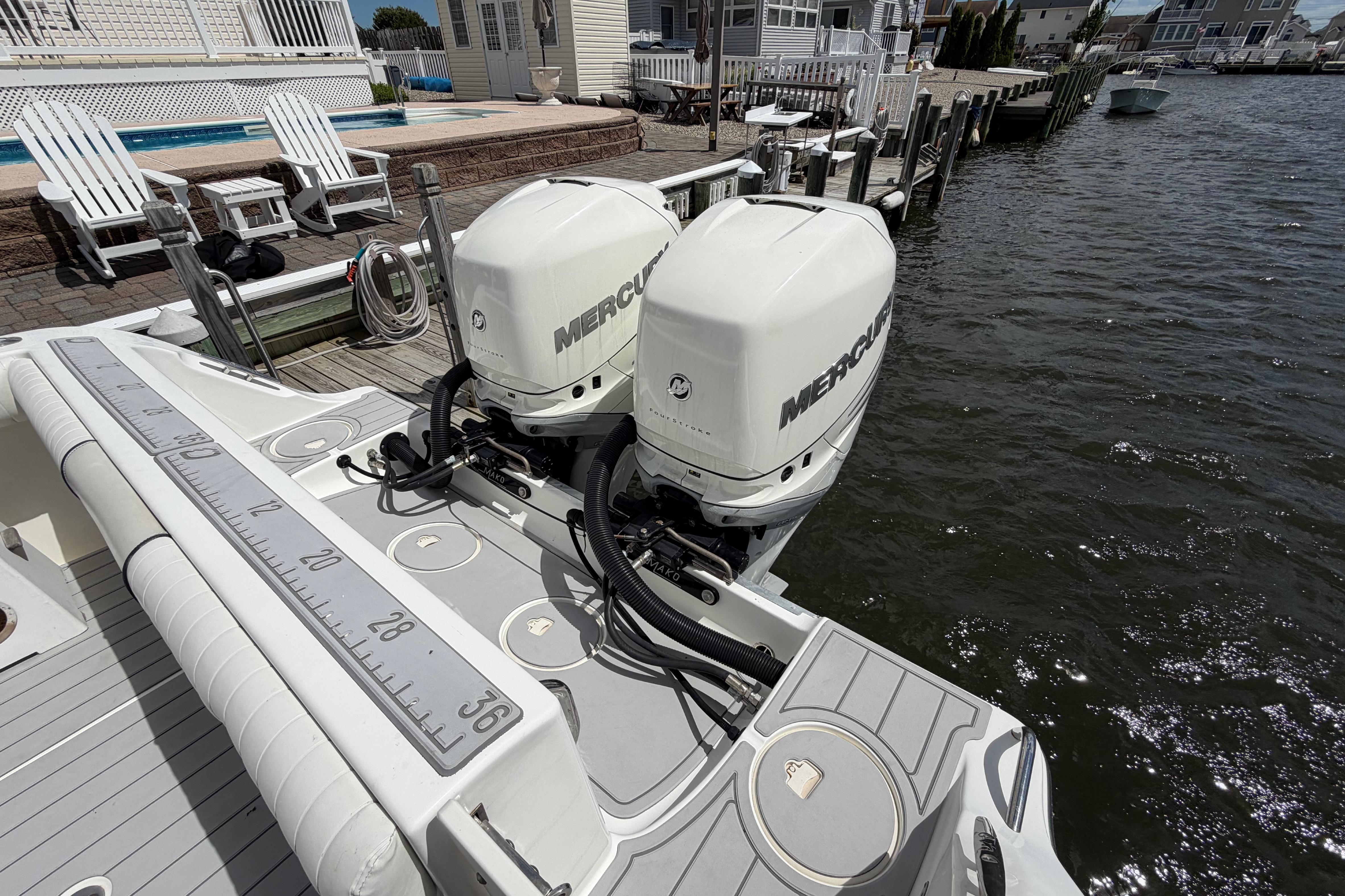 2017 Mako 284 Center Console boat with dual Mercury outboard engines docked by waterfront.