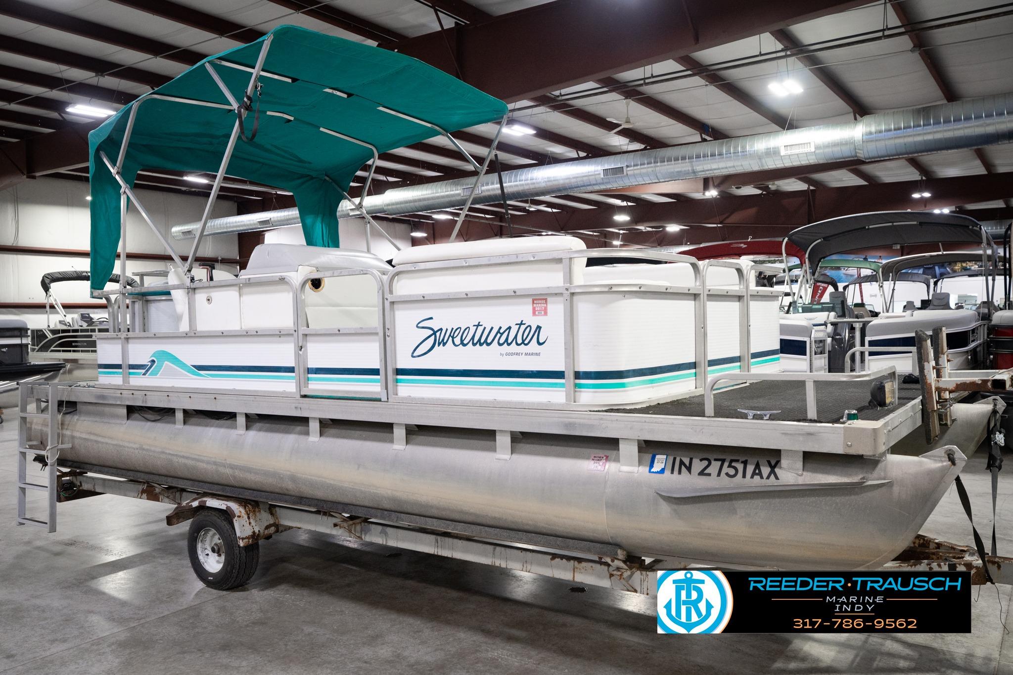 1992 Godfrey Sweetwater pontoon boat with teal canopy in indoor showroom.