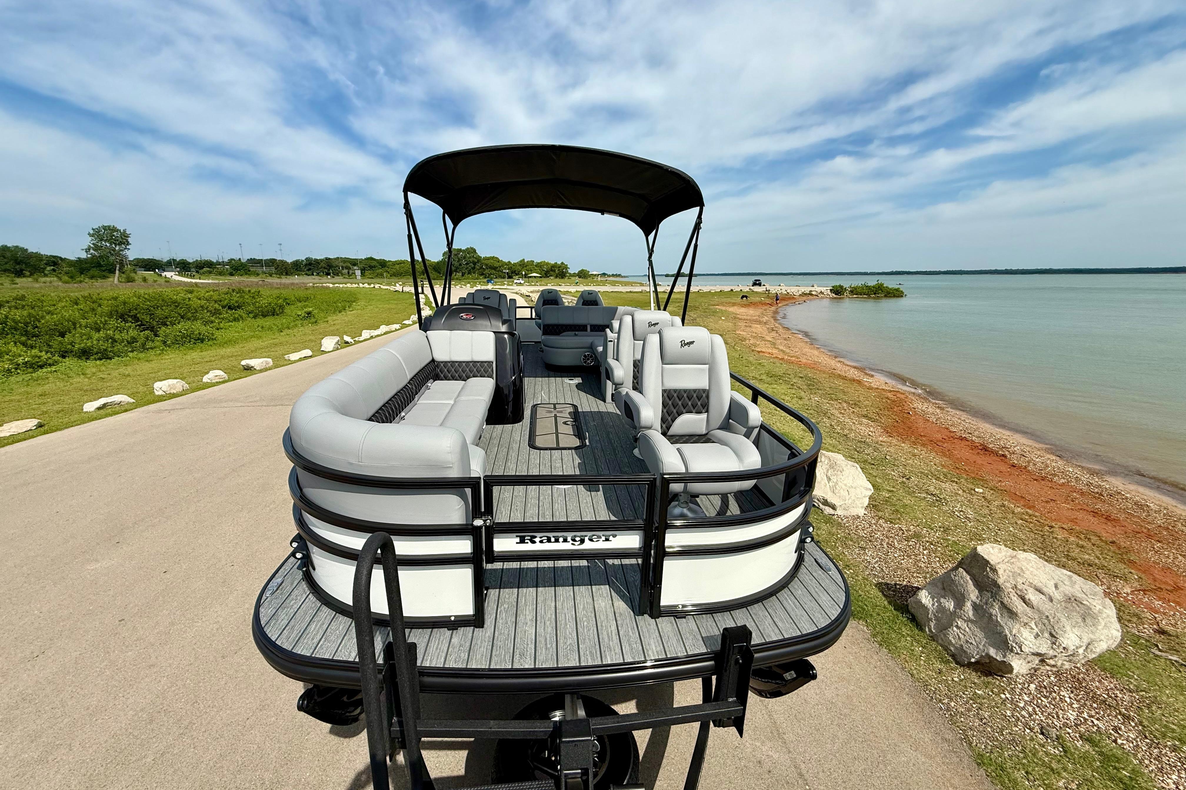 2026 Ranger 223FC pontoon boat parked by a scenic lakeside under a clear sky.