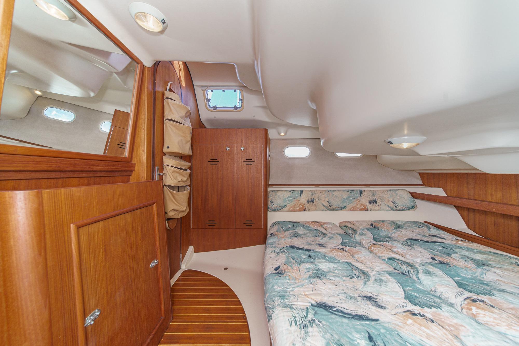 Cozy cabin interior of 1996 Hunter 376 sailboat with wood paneling and patterned bedding.