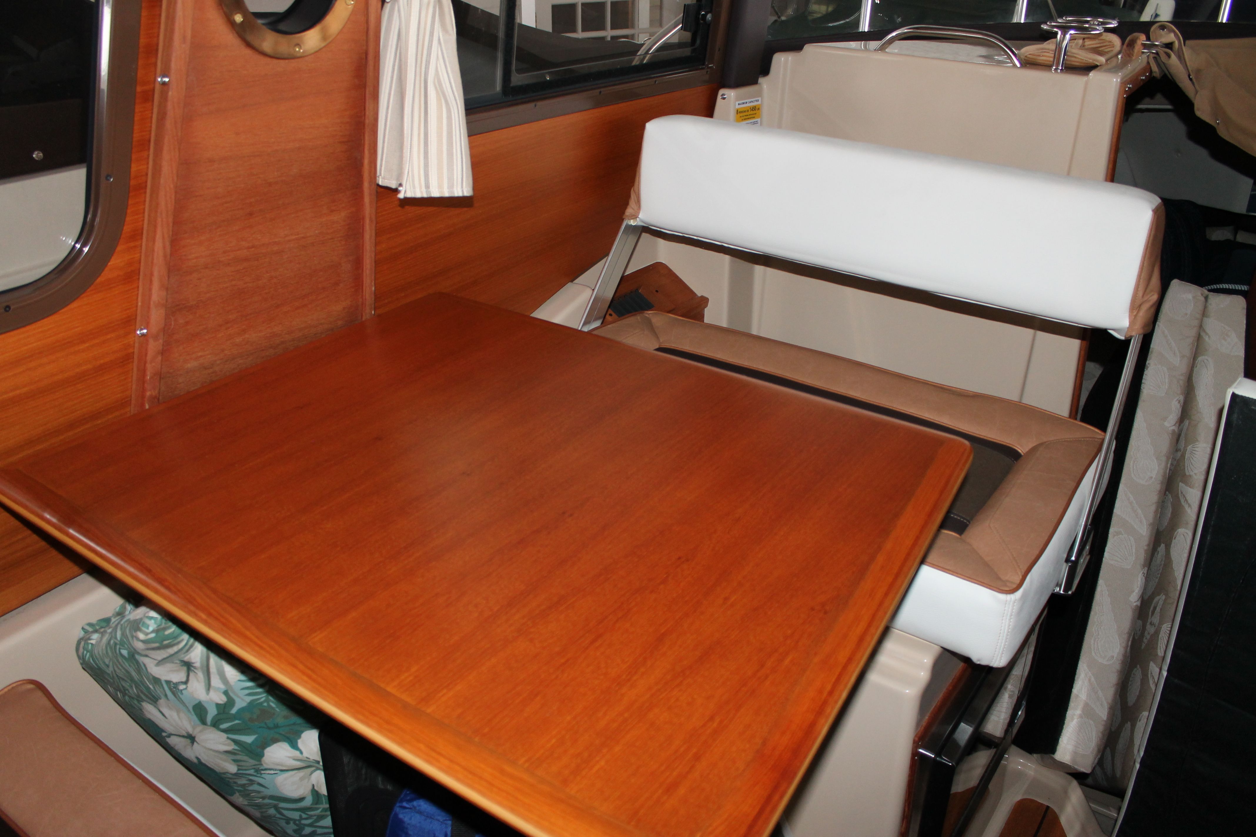 Interior of a 2018 Ranger Tugs R-23 with a wooden table and cushioned seating.