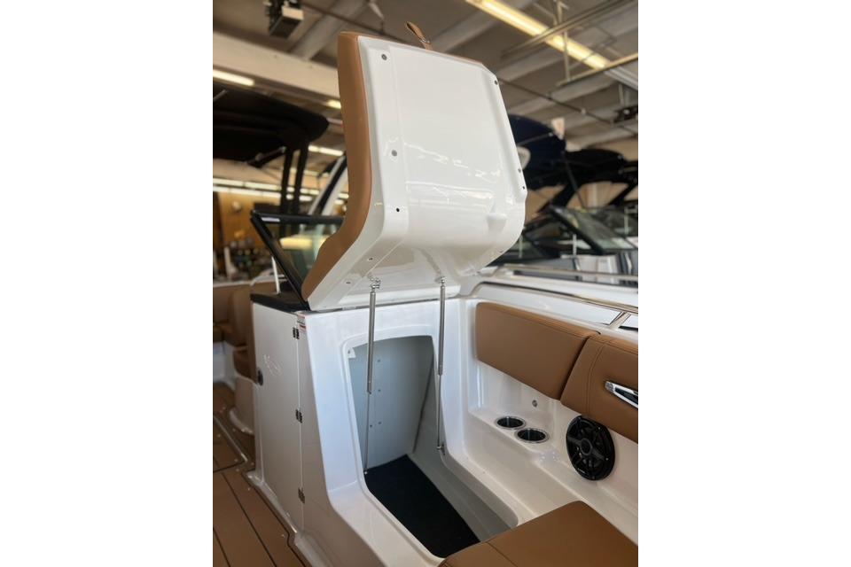 2025 Chaparral 247 SSX boat interior with open storage compartment and tan seating.