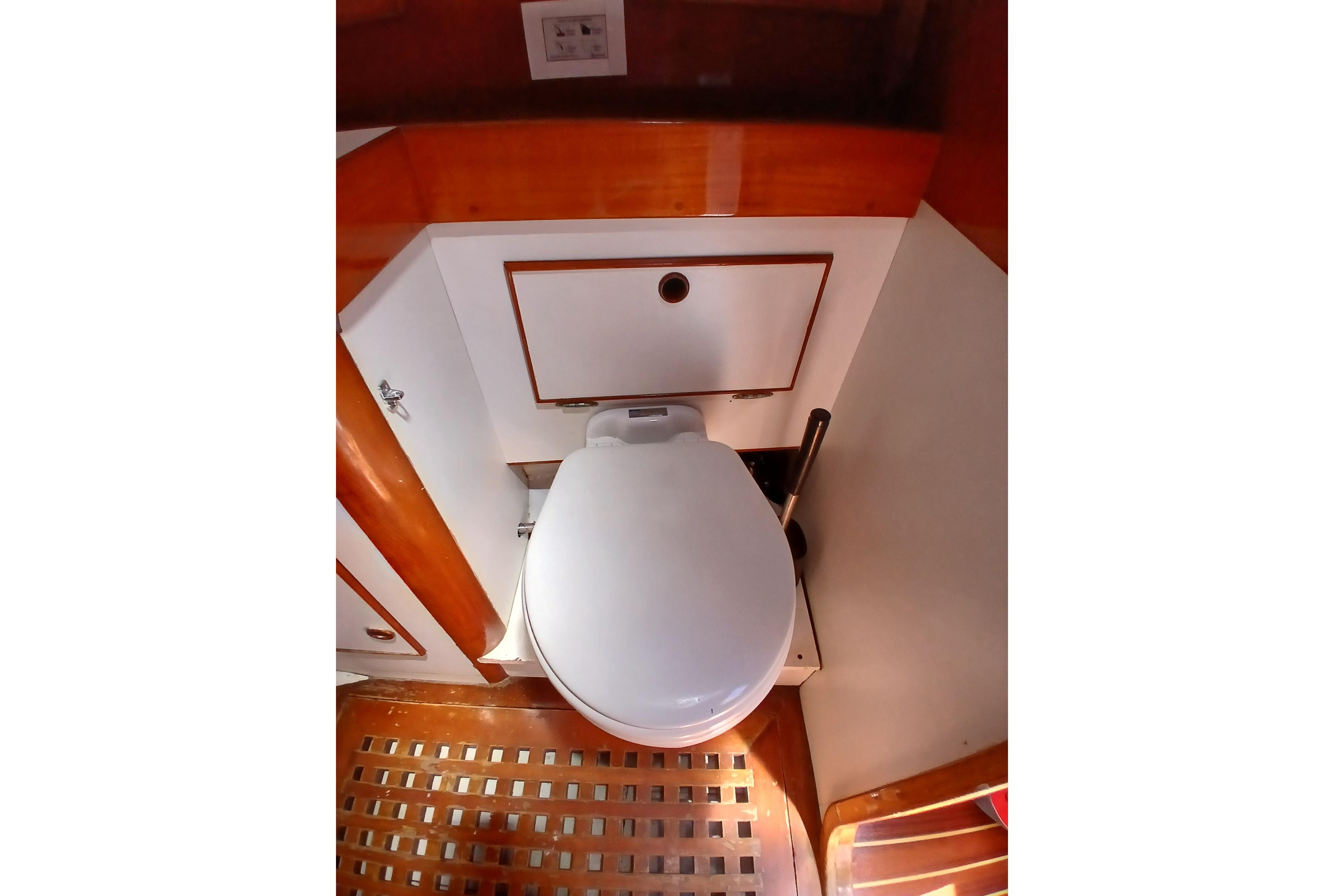 Compact marine bathroom with wooden accents on a 1981 SKYE 51 yacht.
