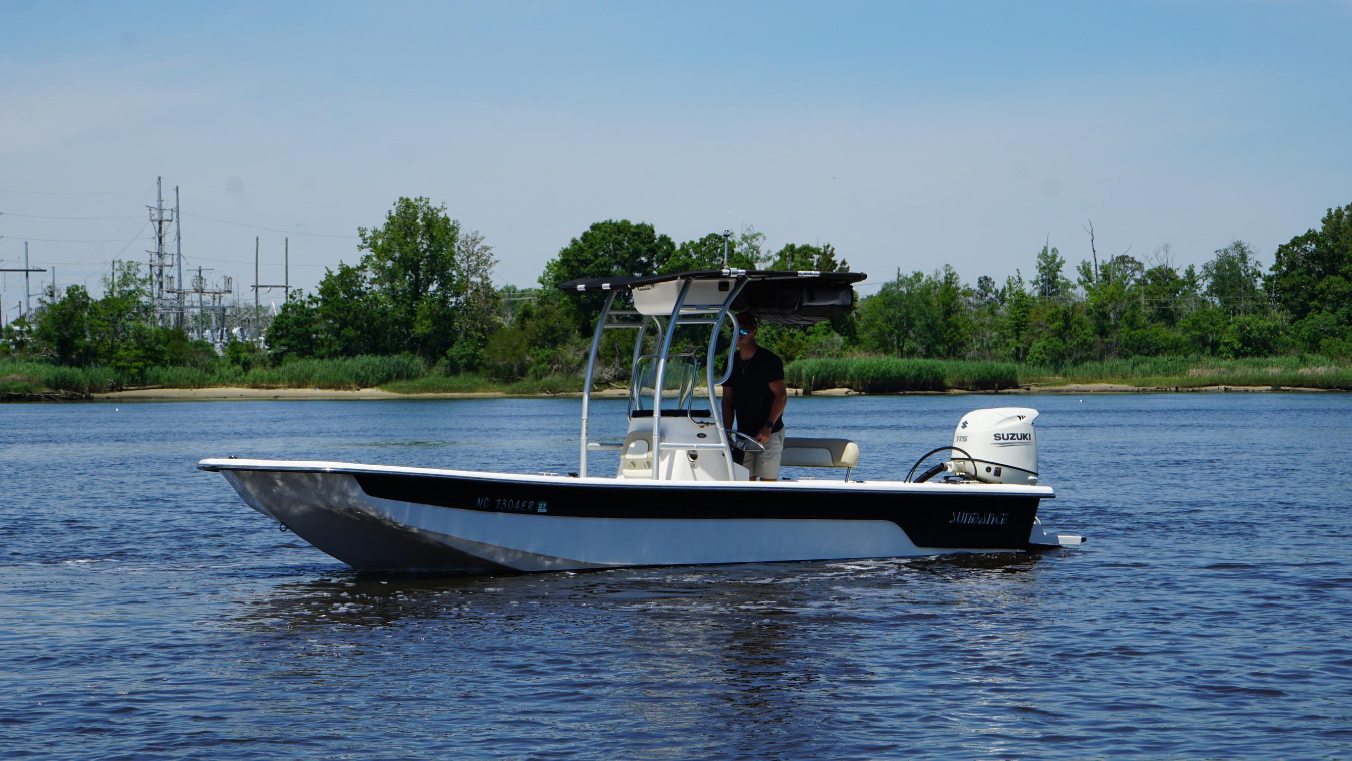 2020 Sundance B22CR boat on a calm river with lush green shoreline.