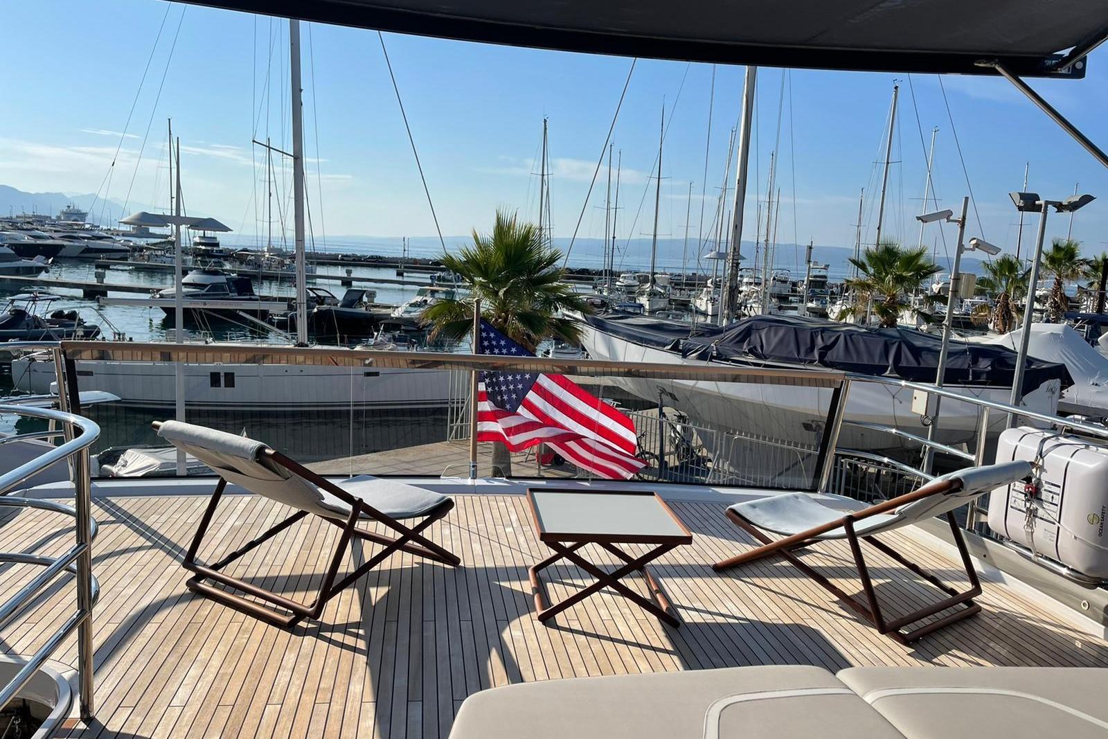 Luxurious 2022 Princess Y85 yacht deck with chairs, table, and marina view.
