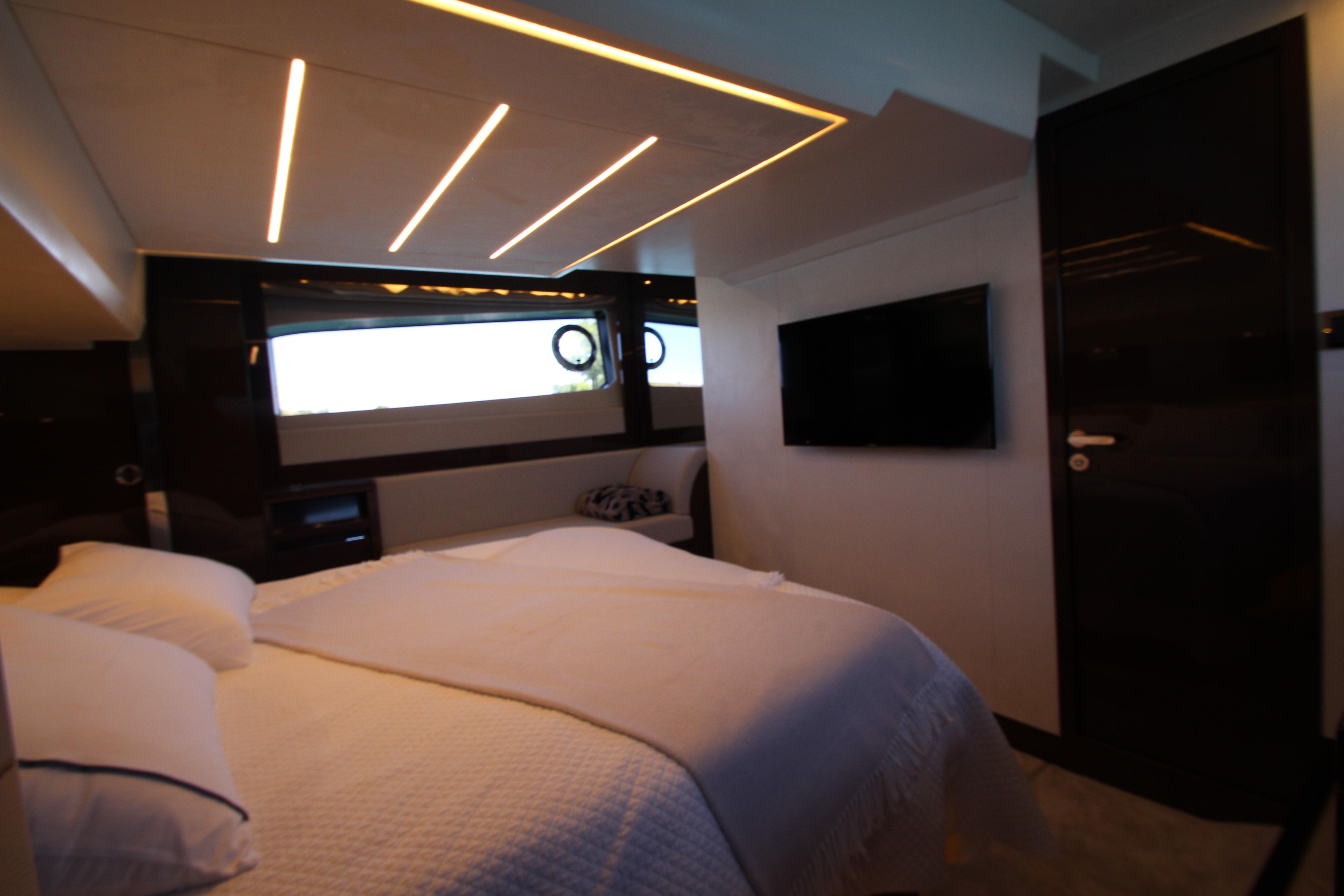 Luxurious bedroom interior of 2022 Prestige 520 yacht with modern lighting and TV.
