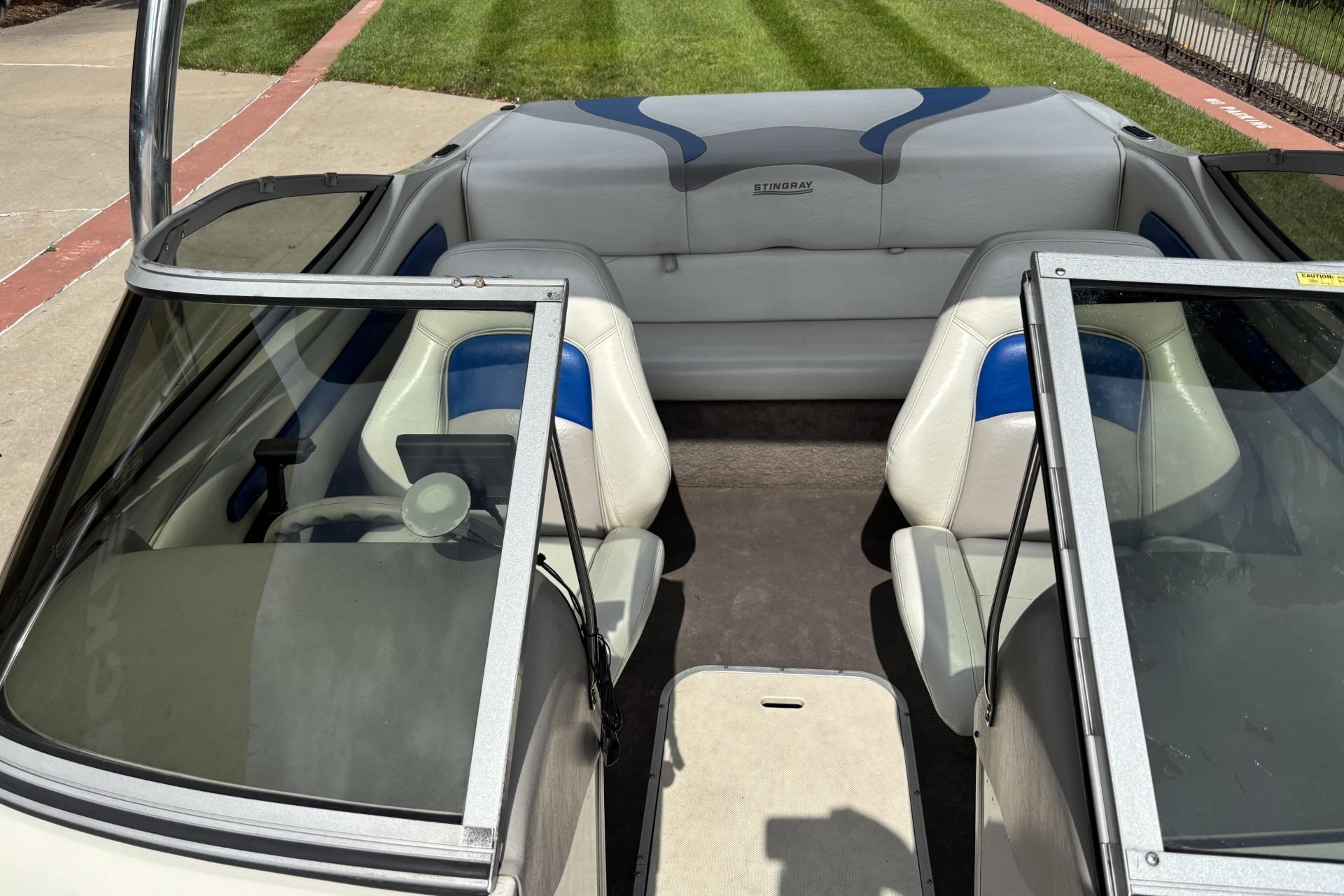 2007 Stingray 180 RX boat interior with white and blue seating, open windshield, and lush green lawn.