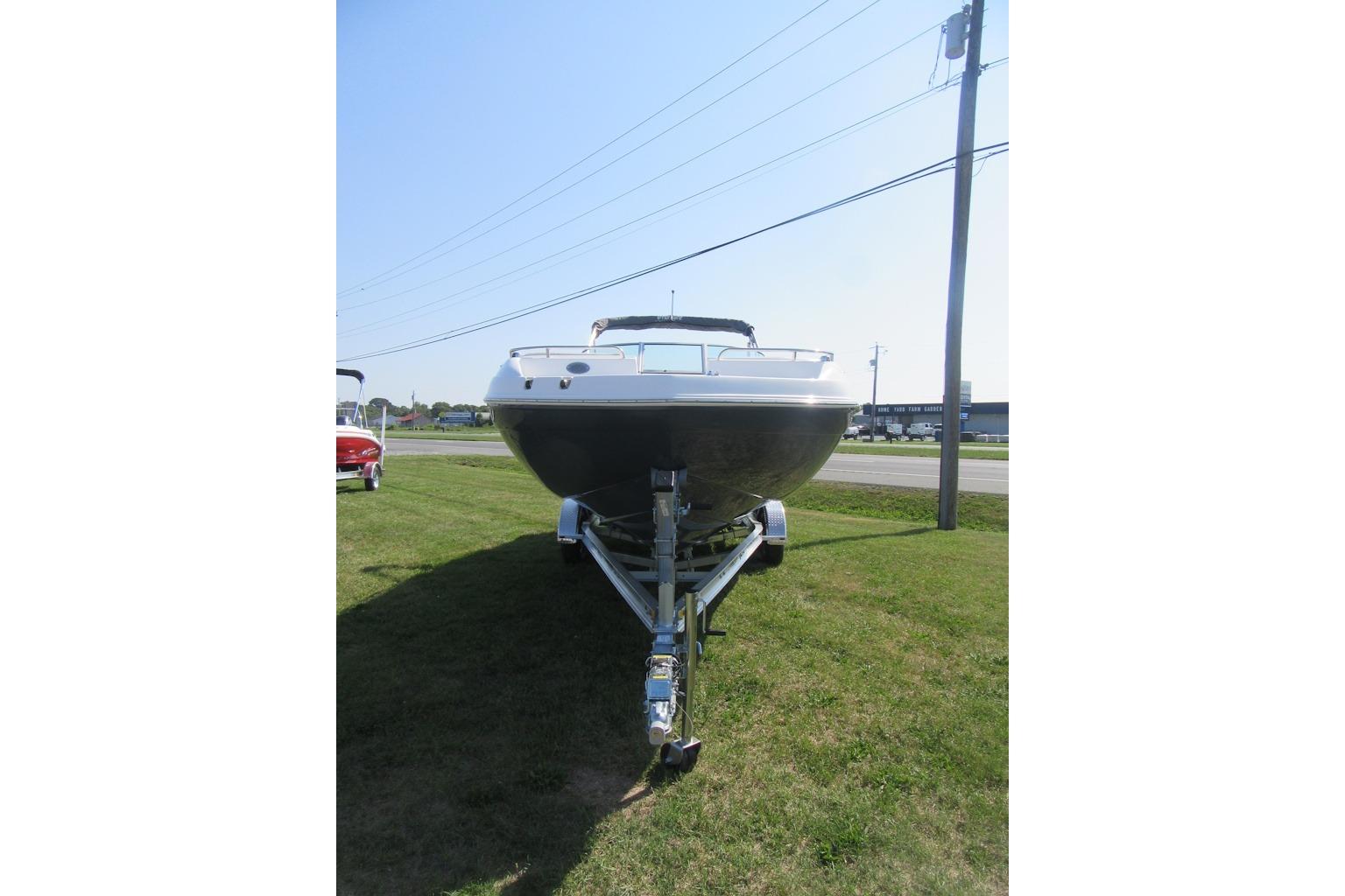 2027 Hurricane SunDeck 2486 OB boat on trailer, parked on grass under clear sky.