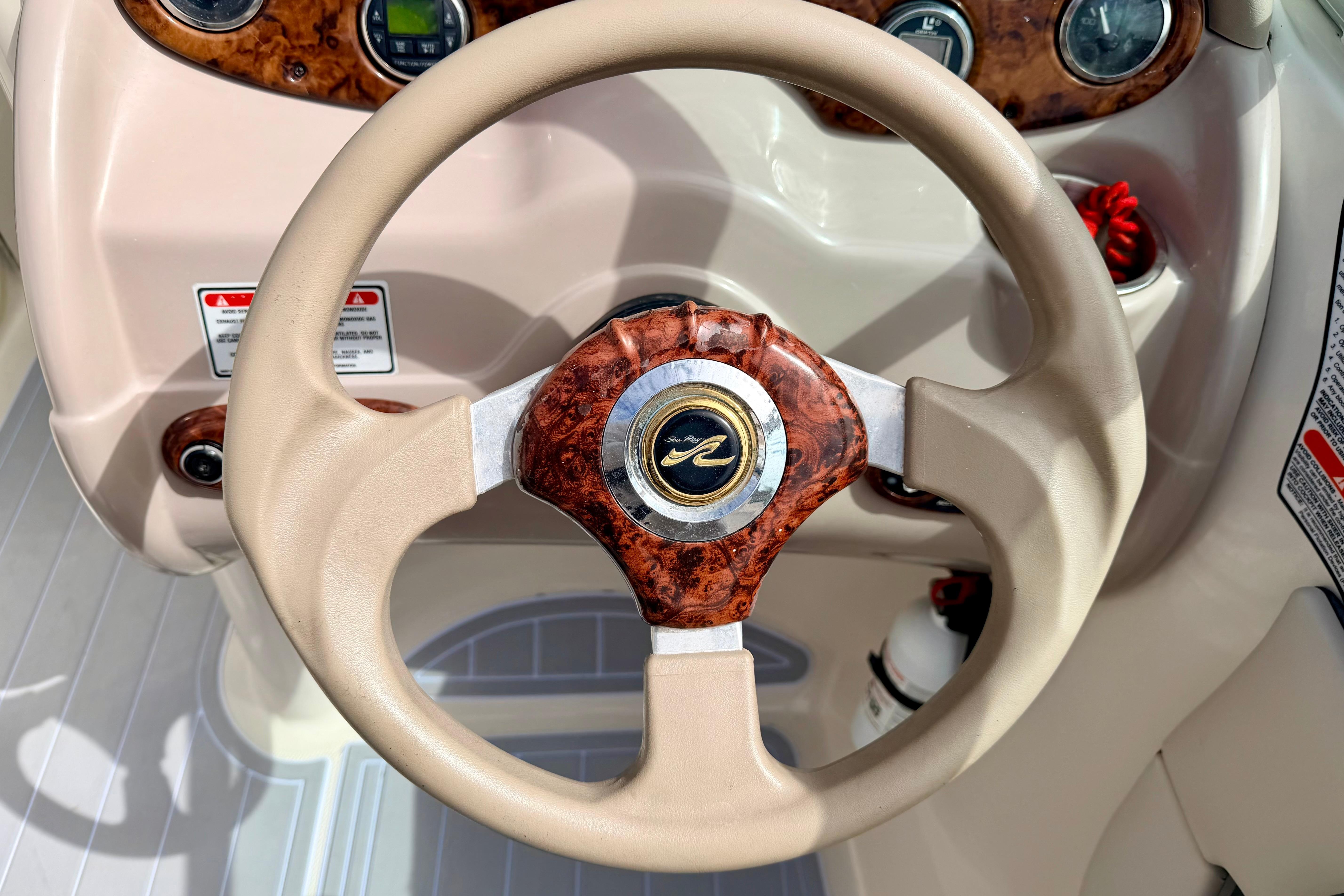 Steering wheel of a 2003 Sea Ray 200 Sundeck boat with wood accents.