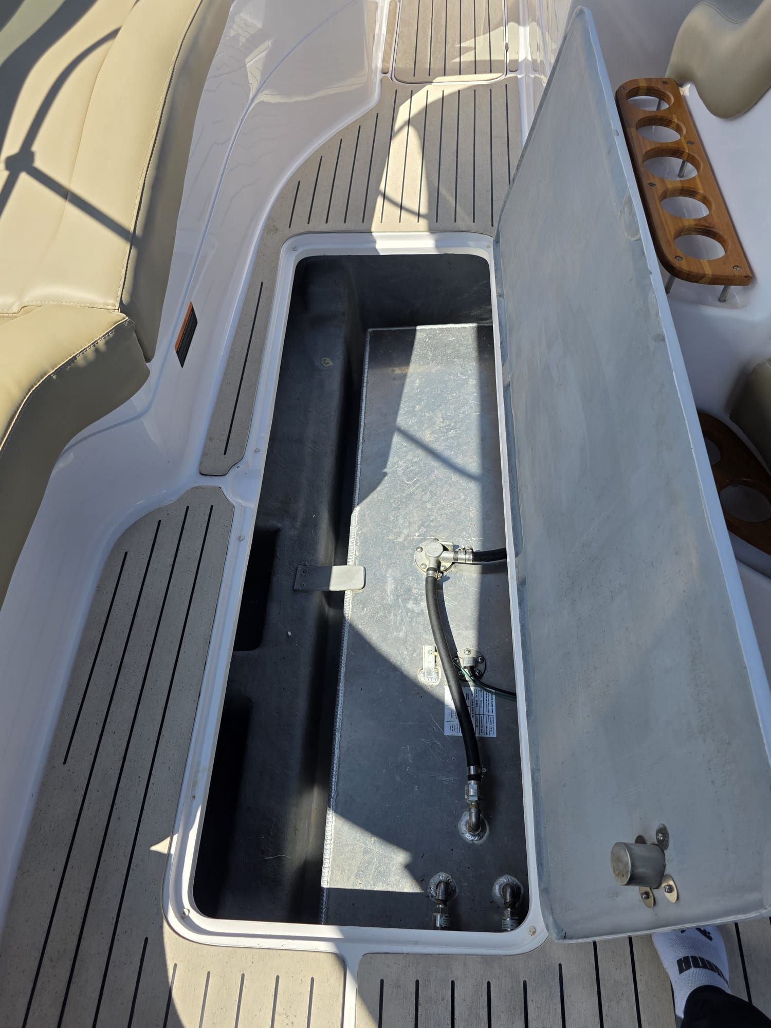 Open storage compartment on a boat with wood details and cushioned seating.