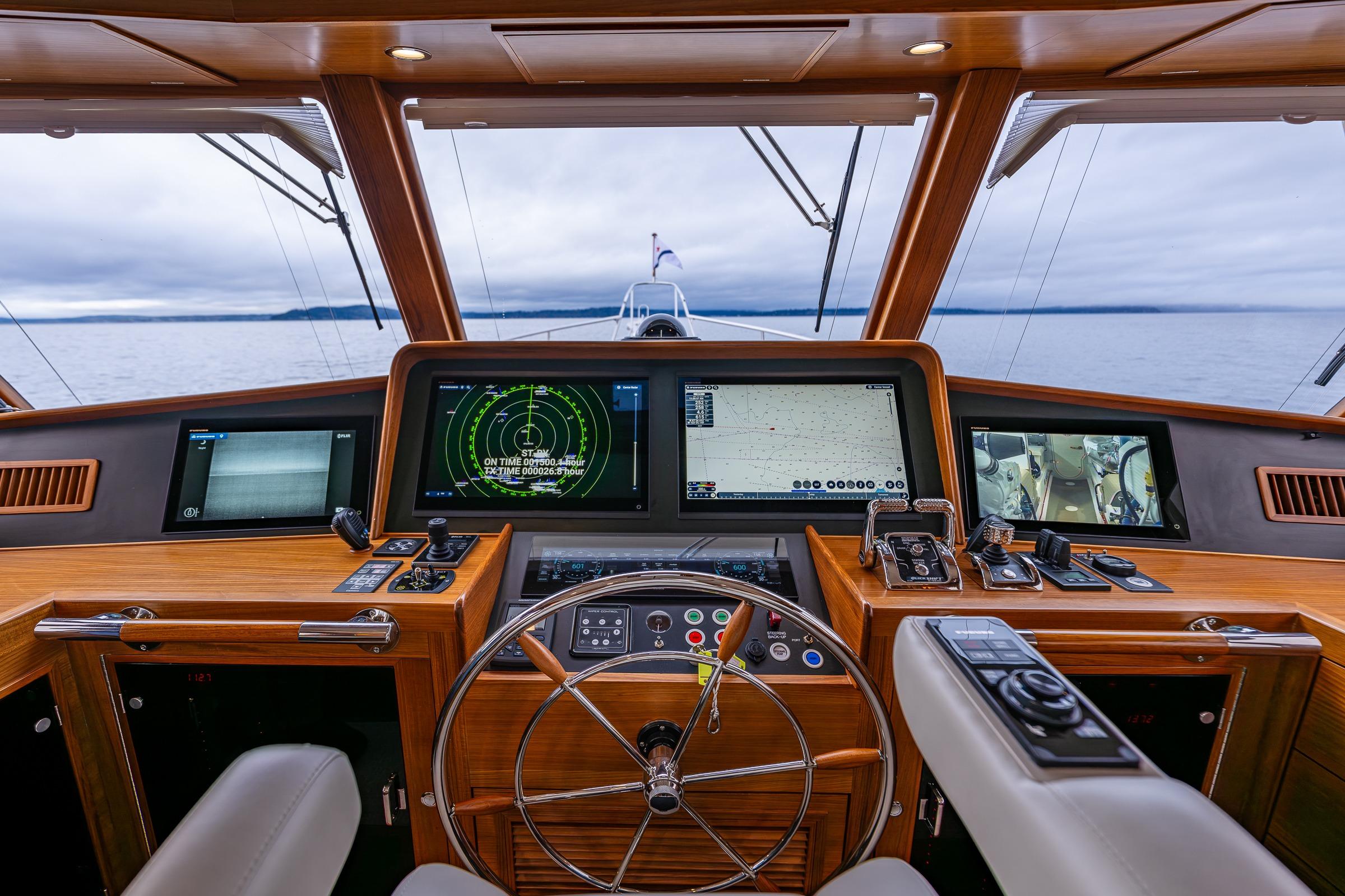 Modern pilothouse of 2026 Fleming 55 yacht with advanced navigation systems and steering wheel.