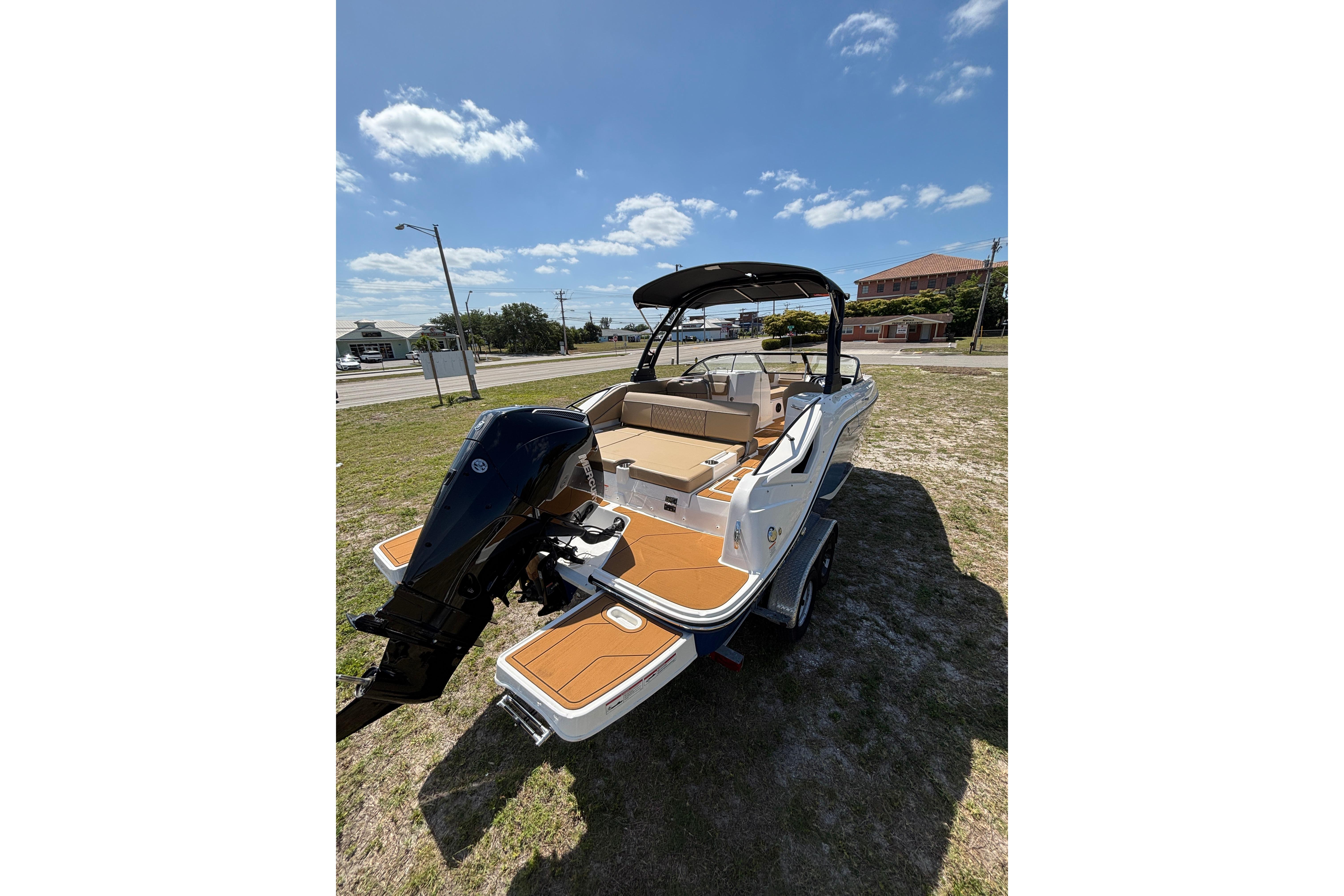 2026 Bayliner D22 boat with outboard motor on grassy area under blue sky.