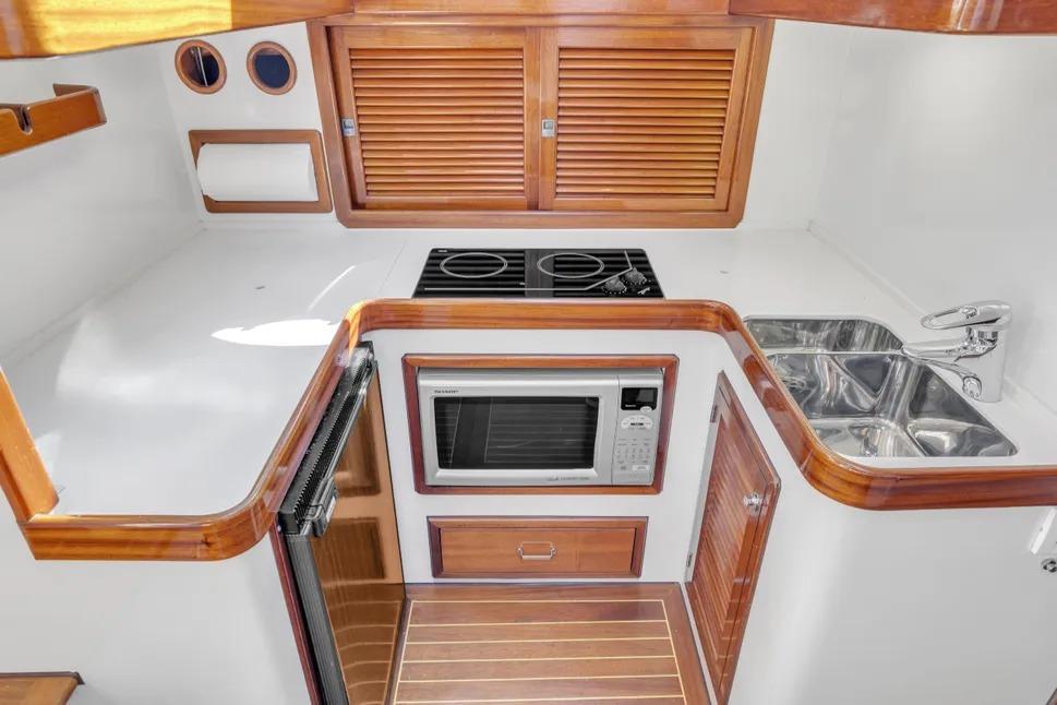Compact kitchen in 2007 Gorbon Custom Downeast 40 yacht with stove, microwave, and sink.