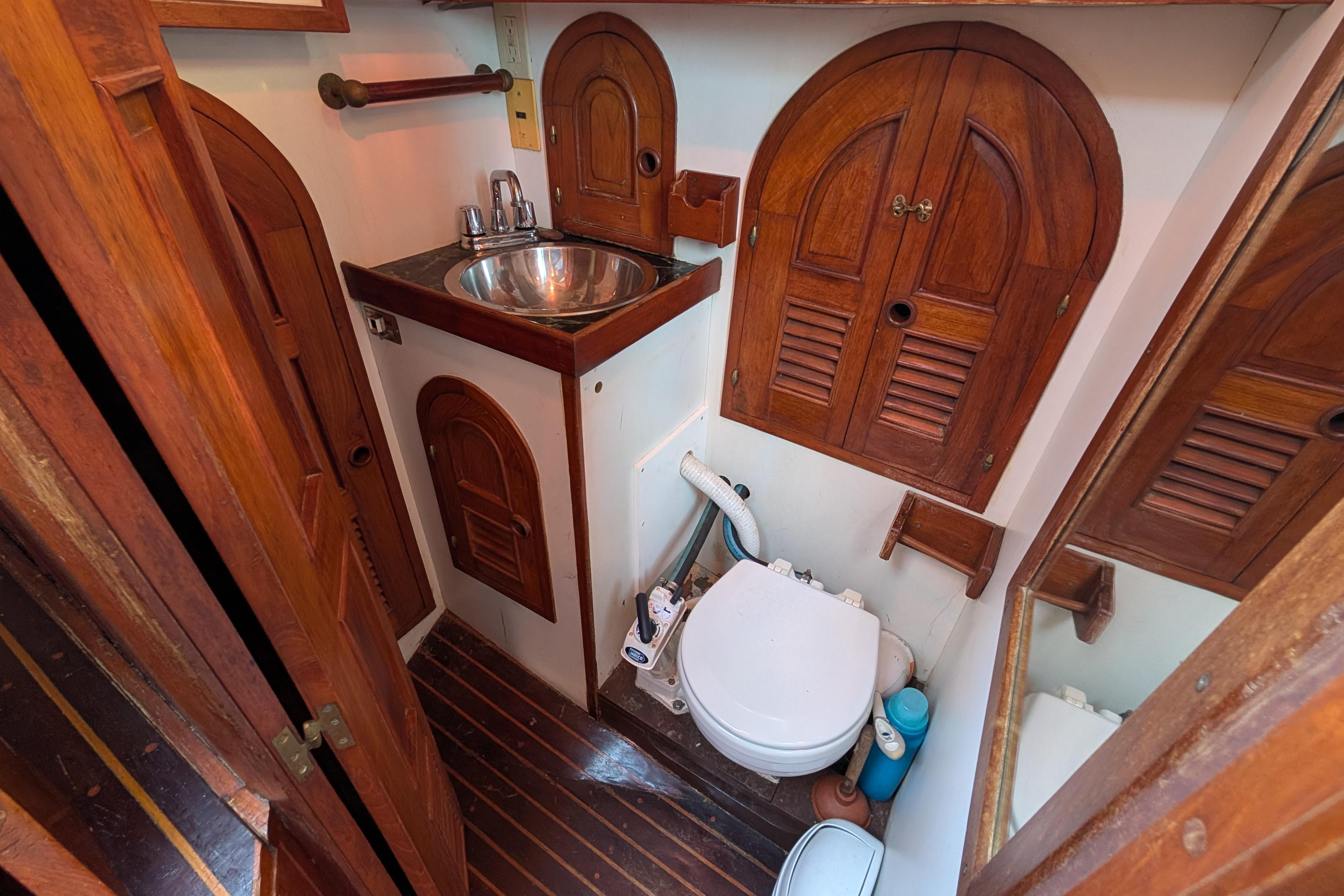 Vintage 1983 Robert Perry 41 yacht bathroom with wooden cabinetry and compact design.