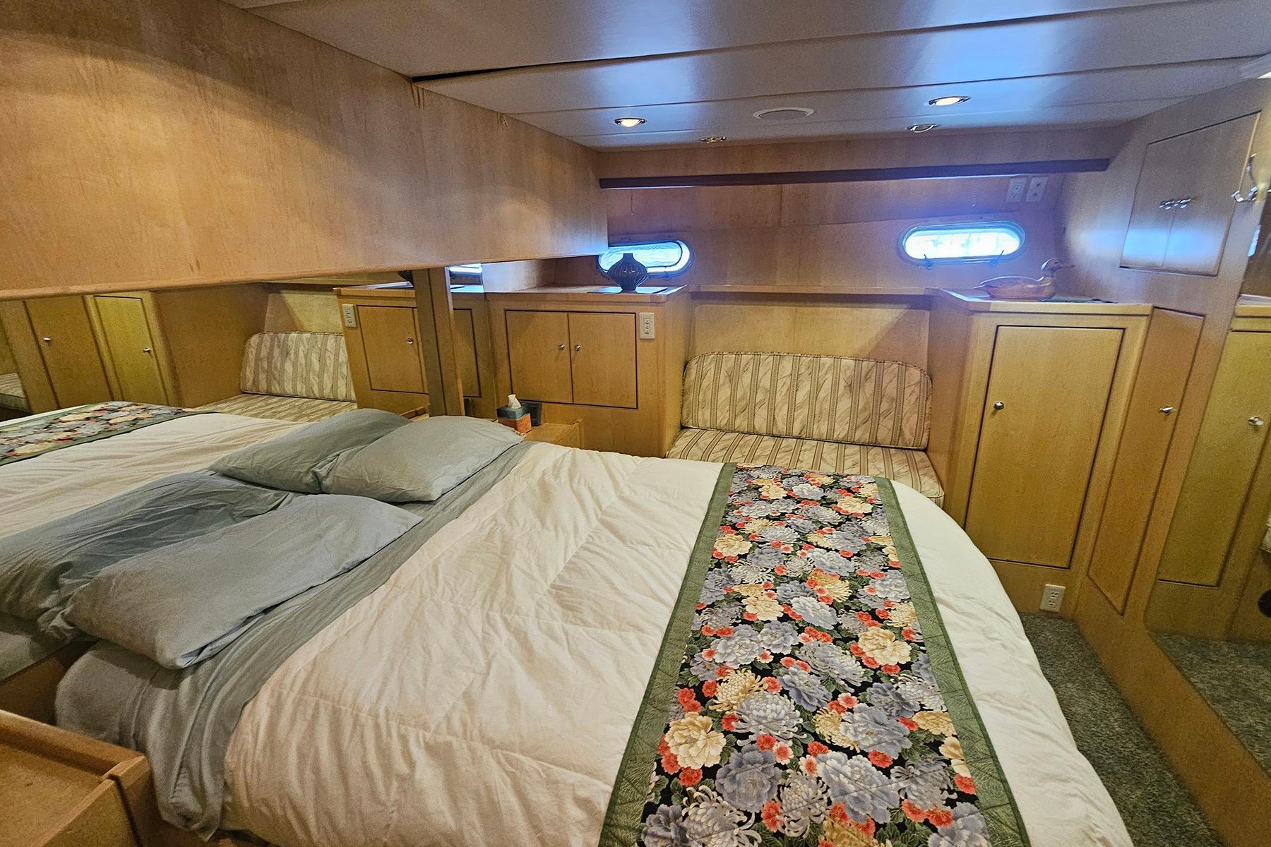Cozy 1995 Symbol 55 yacht bedroom with floral bedspread and wooden cabinetry.