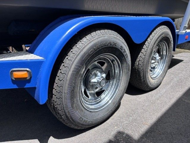 Close-up of a blue boat trailer with two tires.