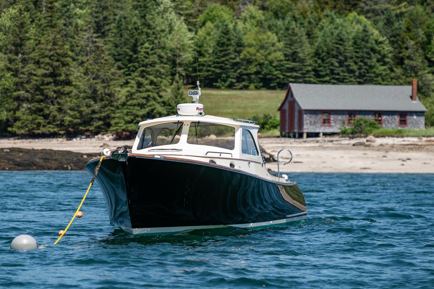 2001 Hinckley Picnic Boat 36 Classic on water near a rustic shoreline.