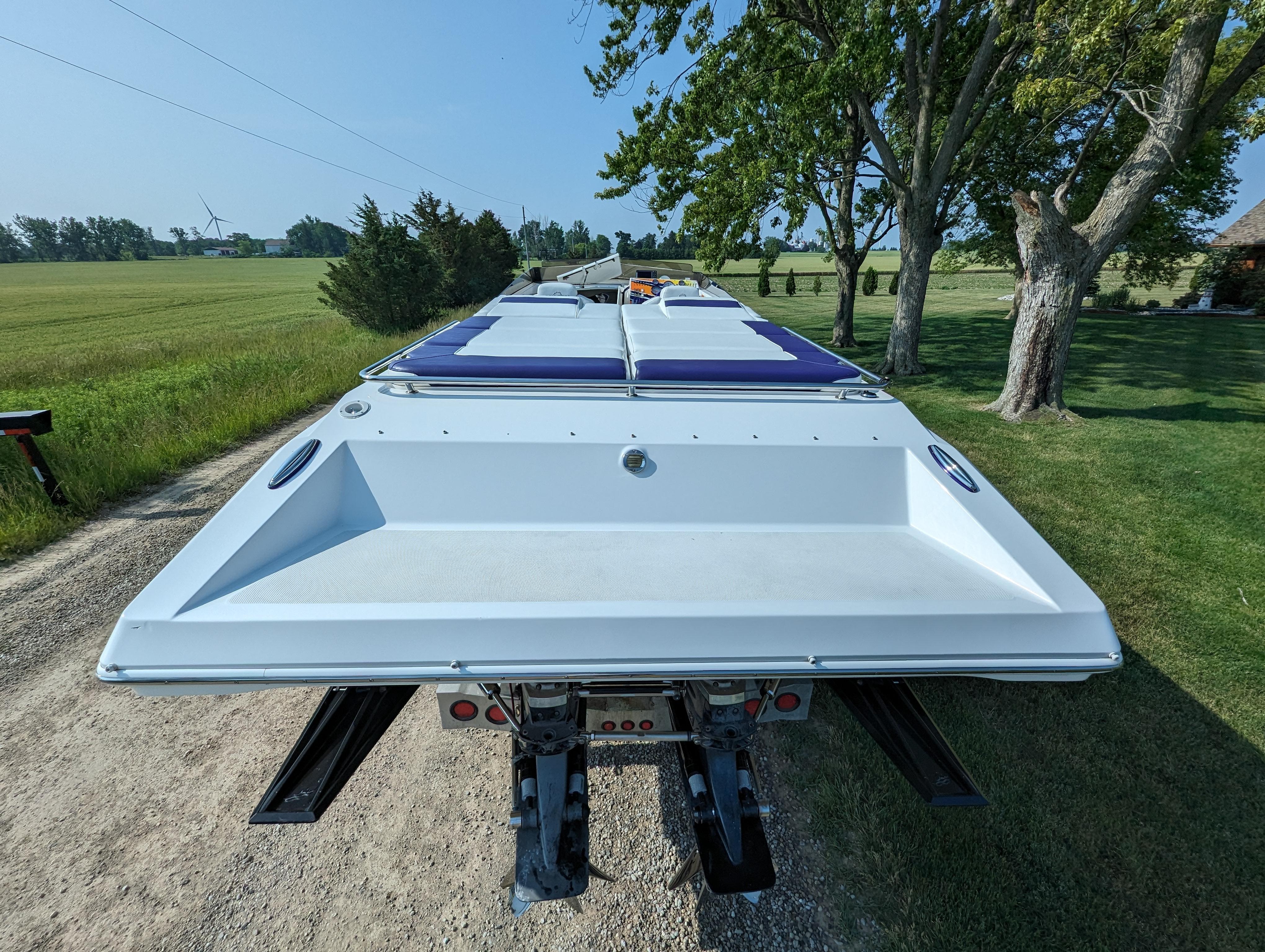 2006 Fountain 42 boat on trailer, parked on rural road with trees and fields.