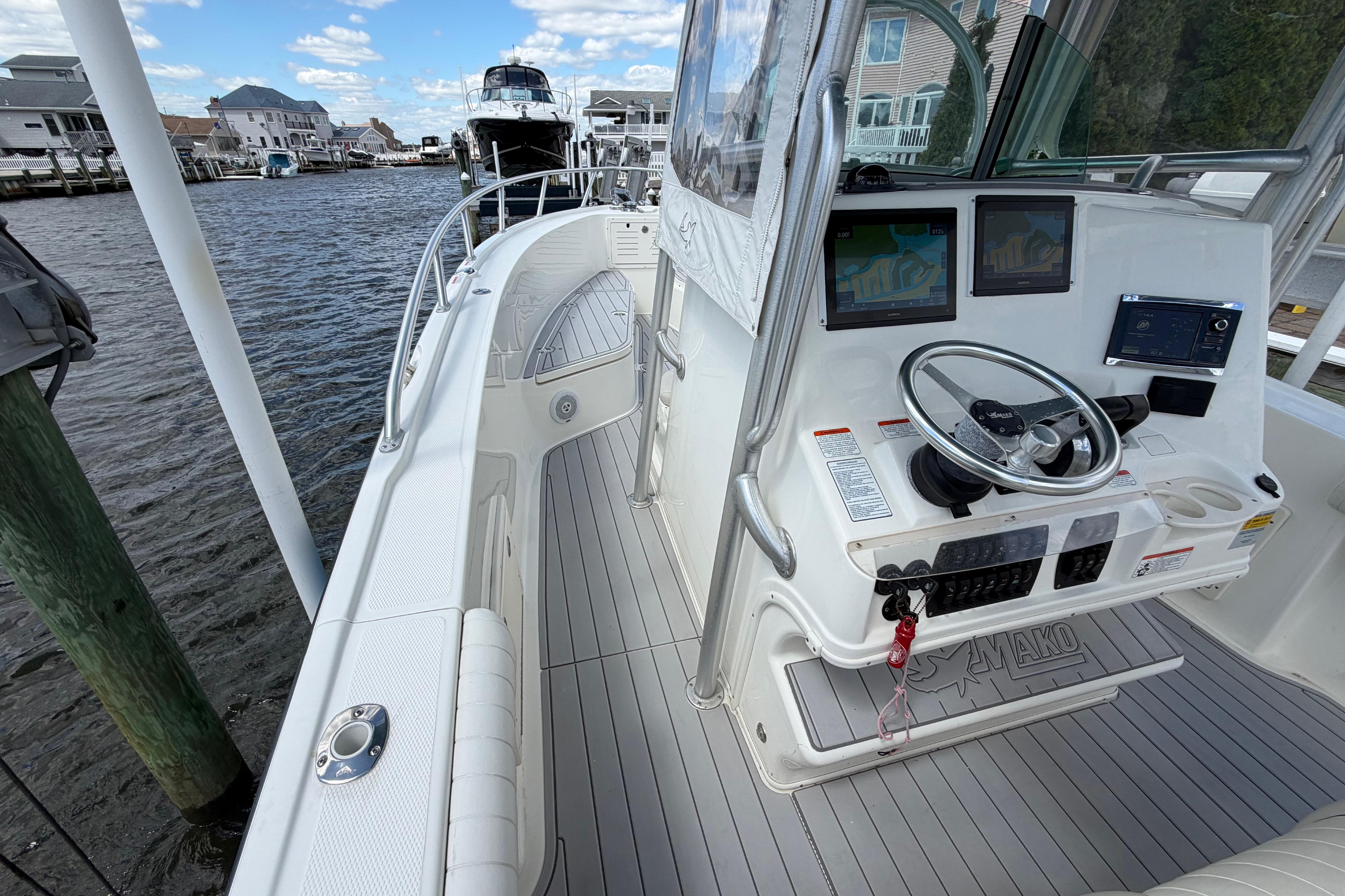 2017 Mako 284 Center Console boat with modern navigation system, docked by waterfront homes.