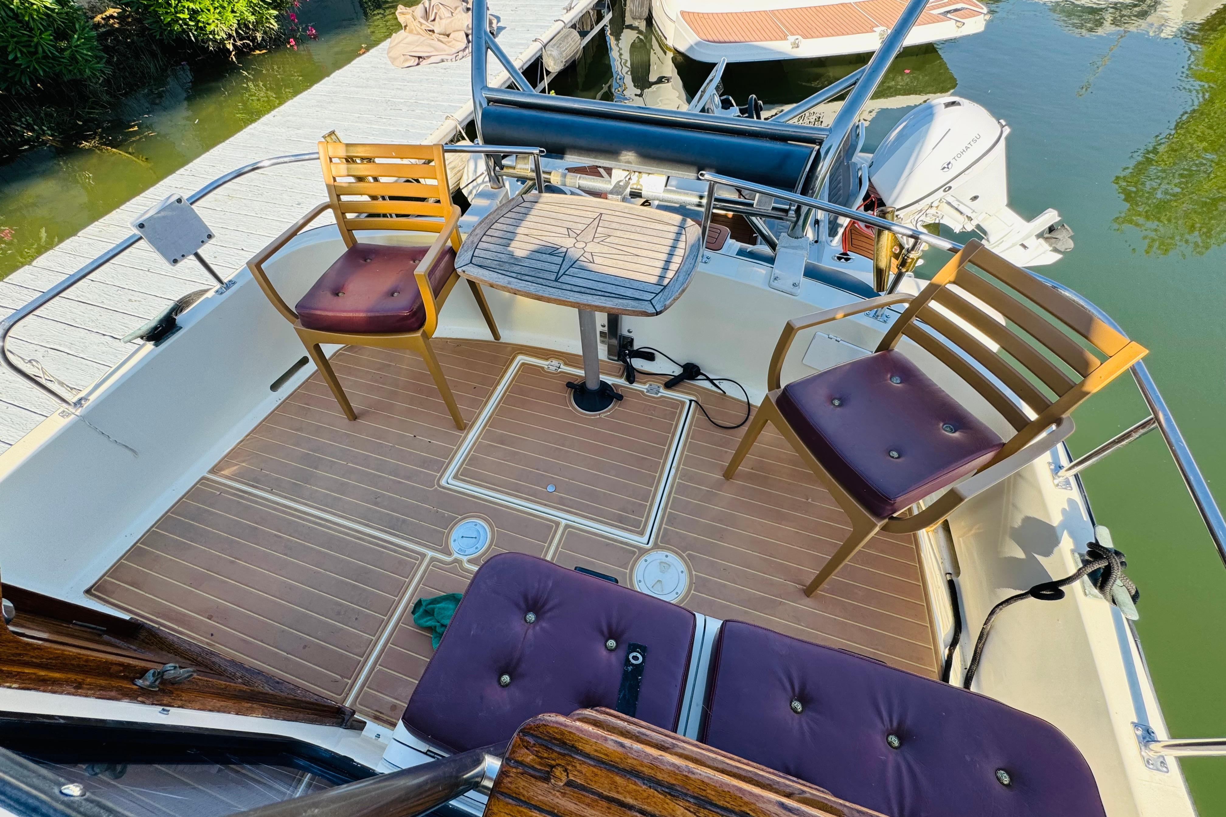 Deck of 1996 Nordic Tug 32 with chairs and table, docked by water.