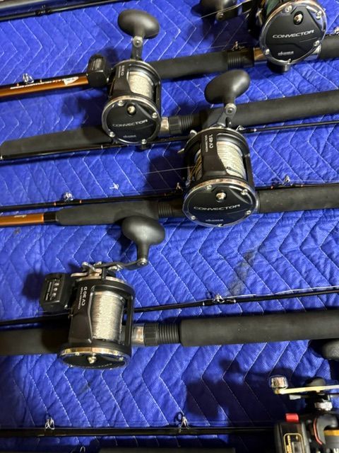 Several fishing rods with reels are laid out on a blue blanket.