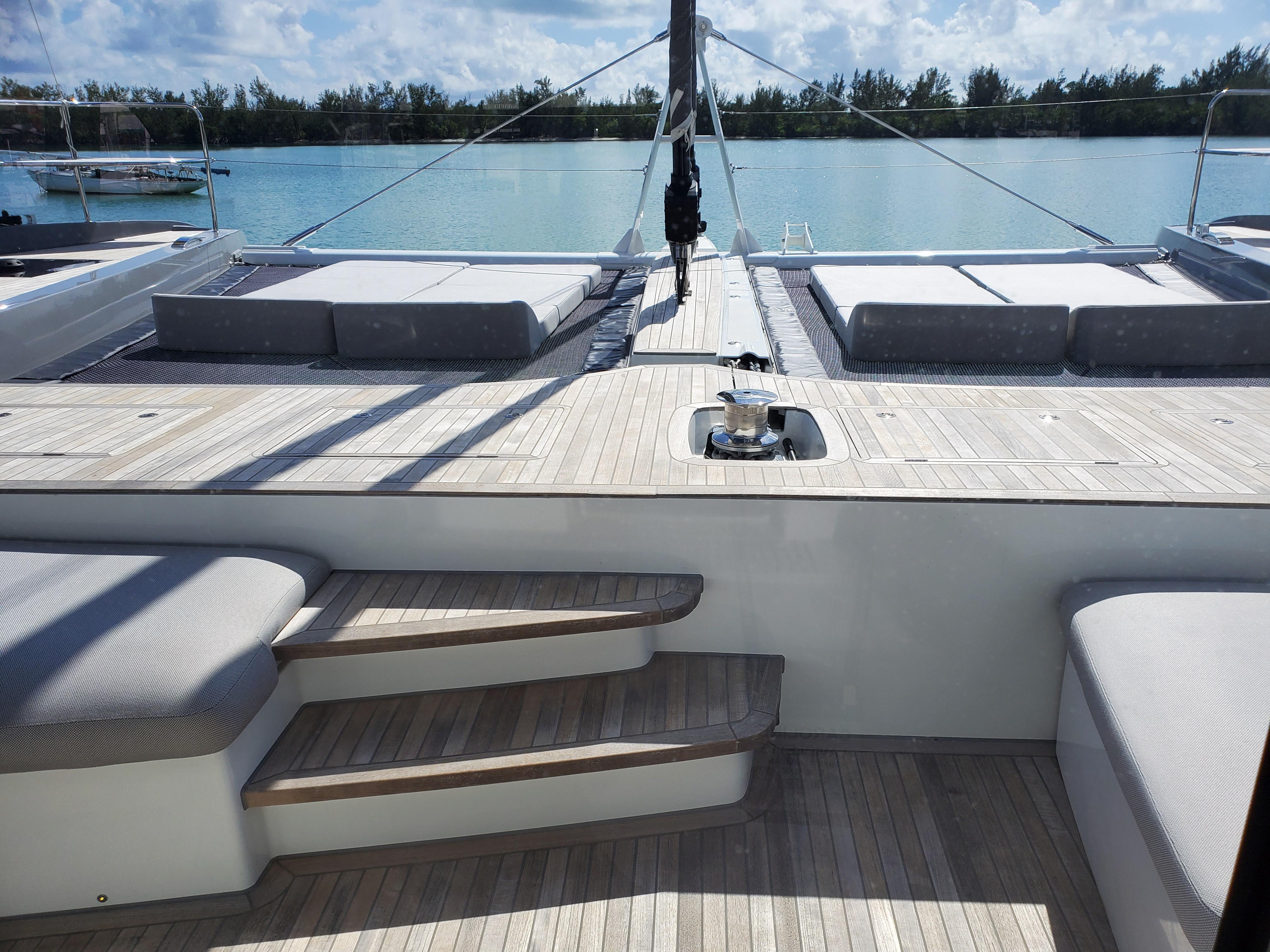 Luxurious Lagoon SEVENTY 7 yacht deck with seating, overlooking serene water and distant trees.
