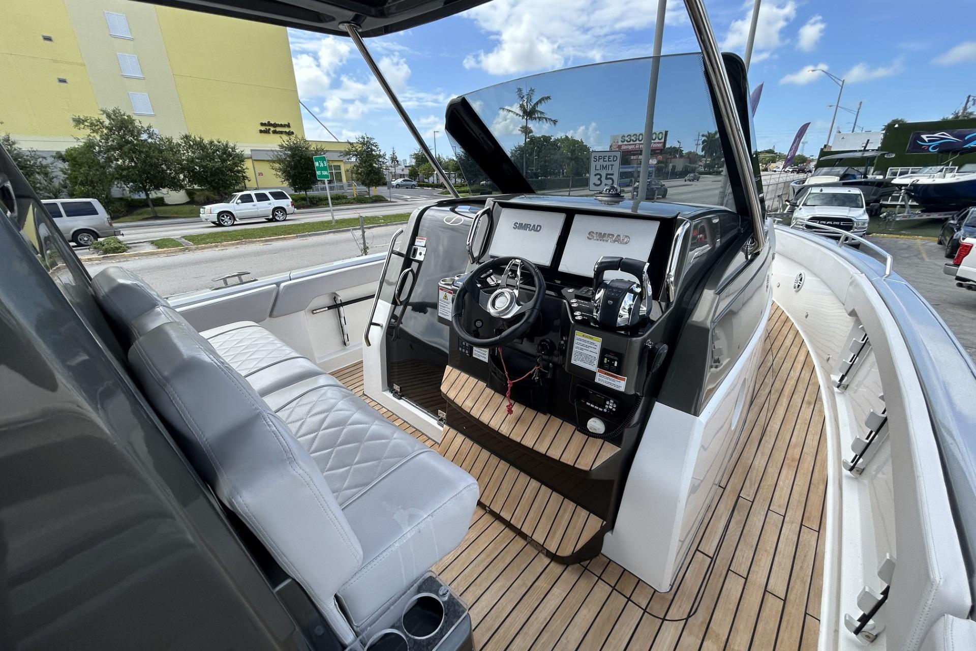 2023 Schaefer V33 boat cockpit with modern controls and seating, docked near a road.