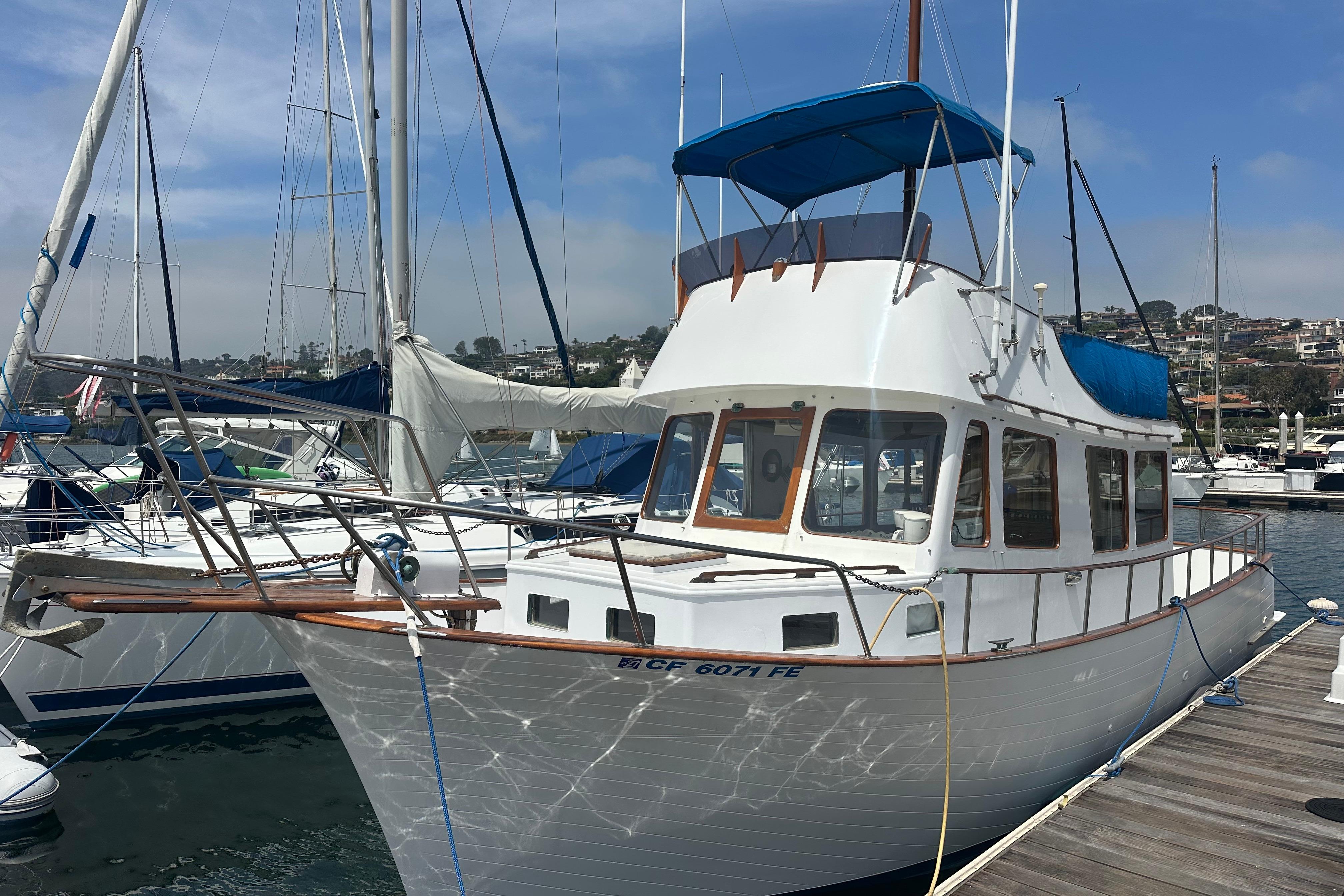 1973 CHB 33 boat docked at marina, featuring classic design and blue canopy.