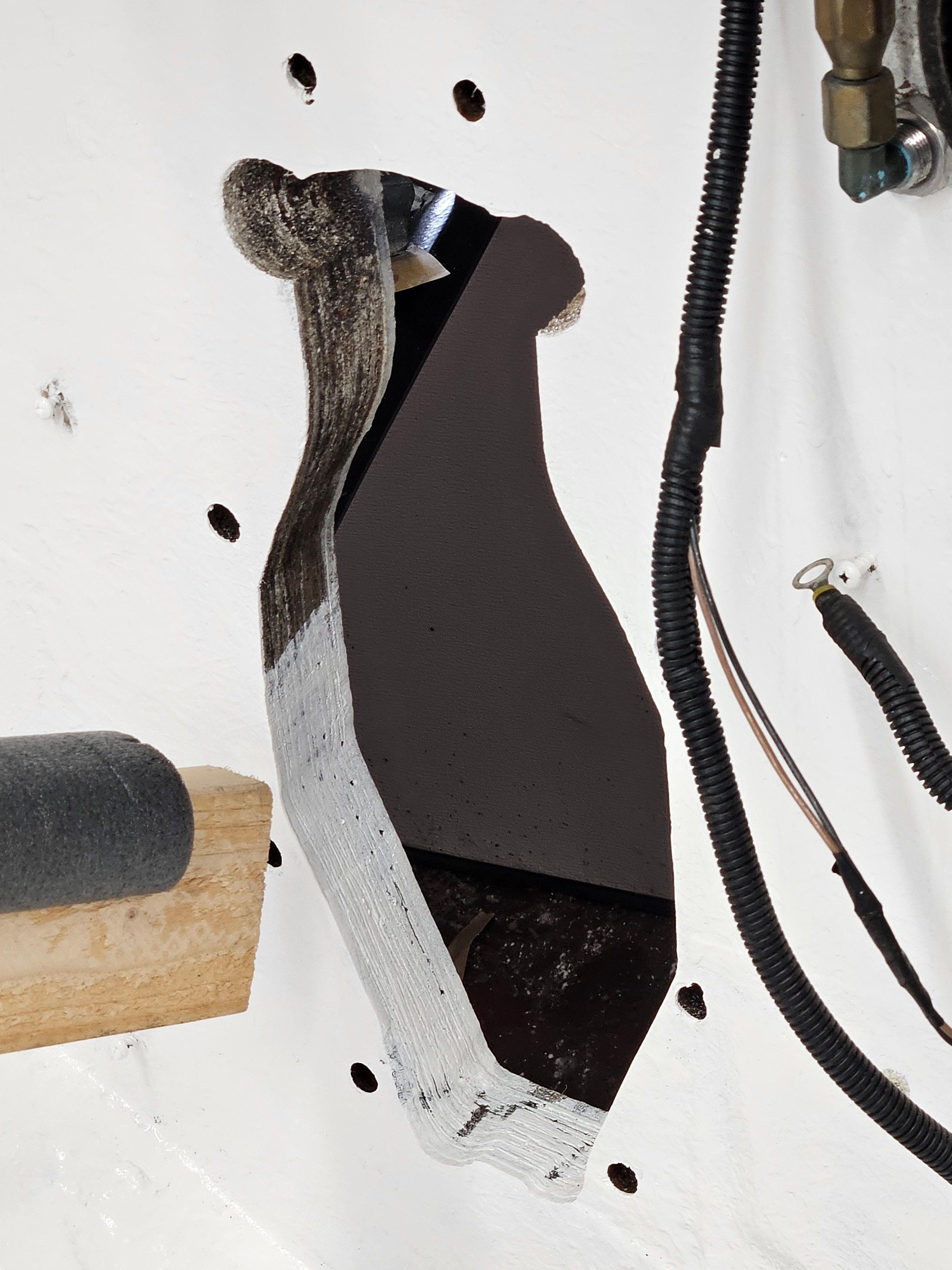 A damaged area in a boat hull with exposed wires and a hole.