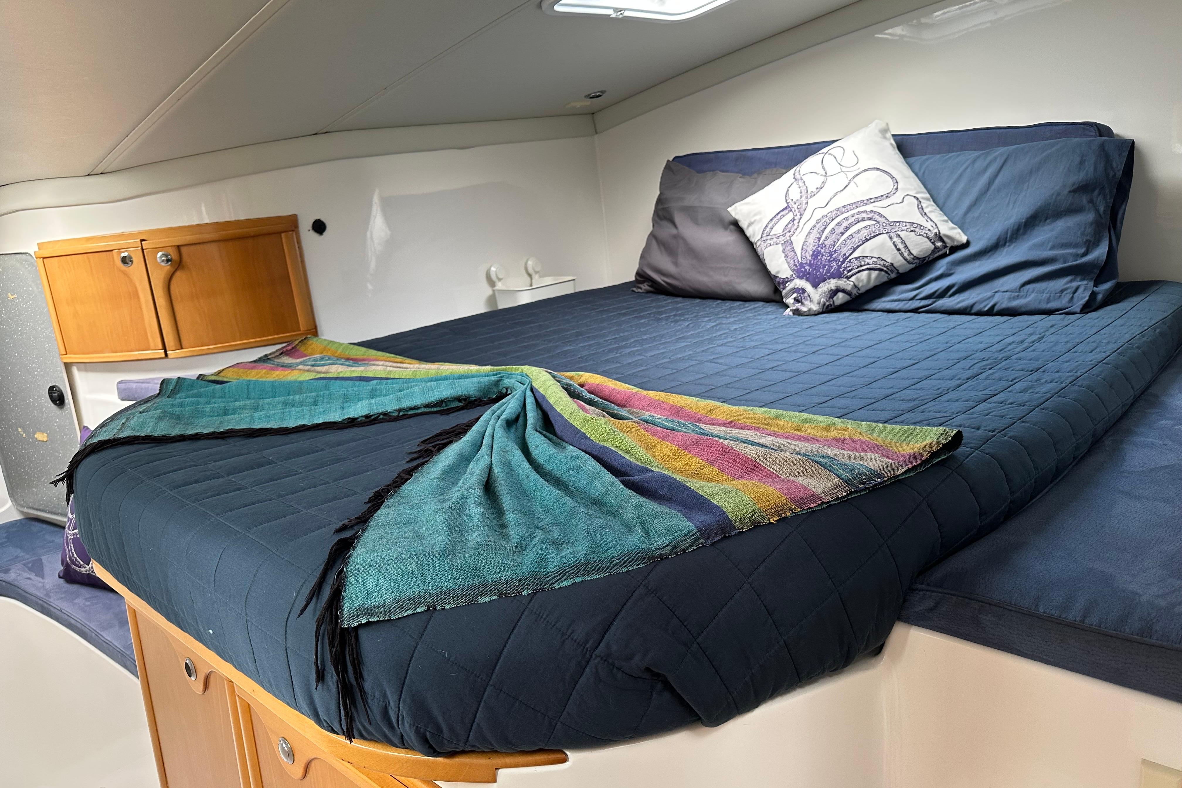 Cozy cabin interior of 2005 Seawind 1160 catamaran with comfortable bedding and colorful decor.