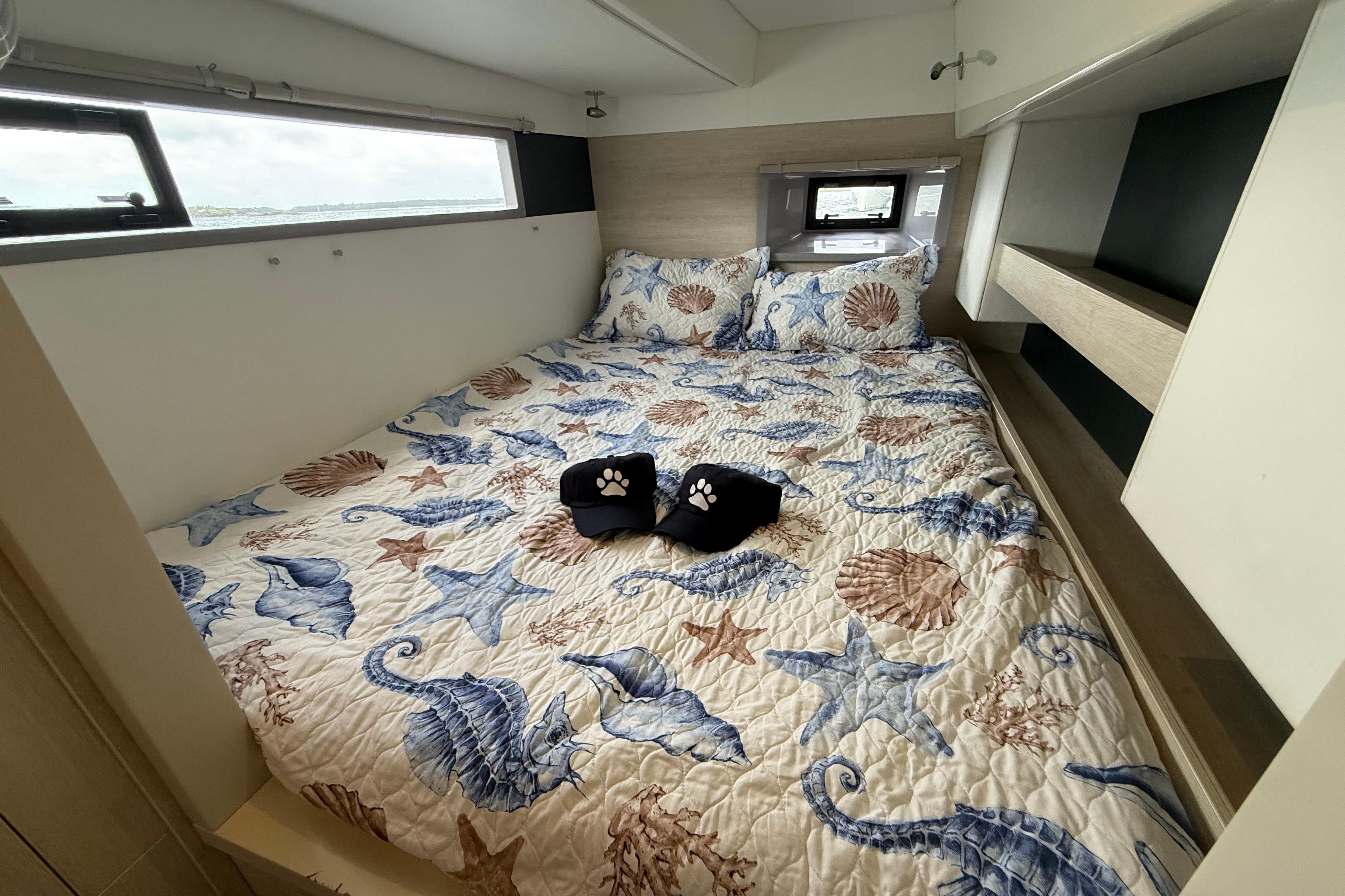Cozy bedroom in 2021 Leopard 43 Powercat with nautical-themed bedding and window view.