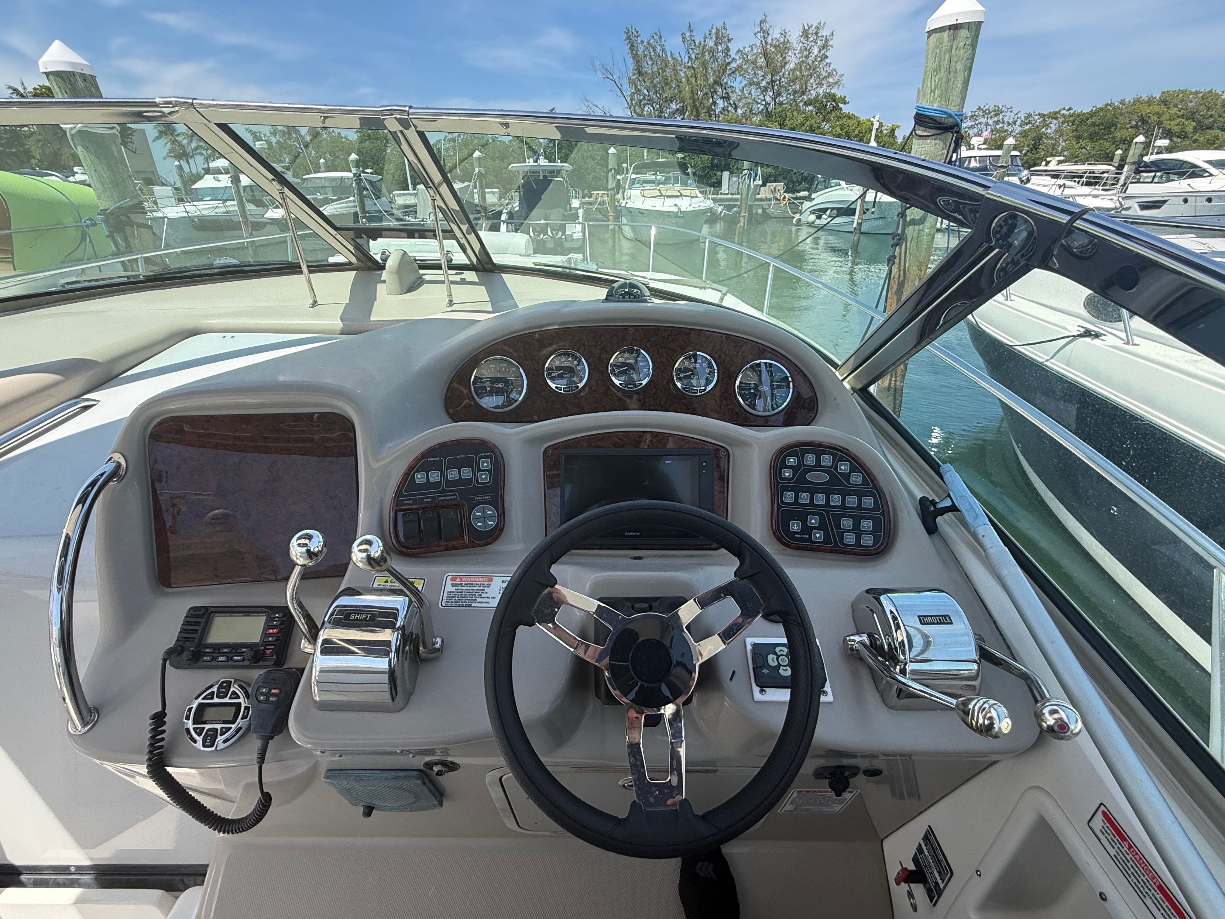 The image shows the helm of a 2006 Sea Ray Sundancer 320 docked at a marina.