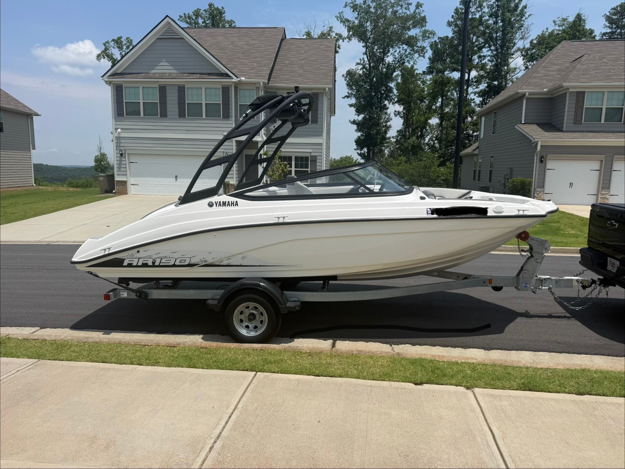 Yamaha AR190 boat from 2023 parked on a trailer in a residential area.