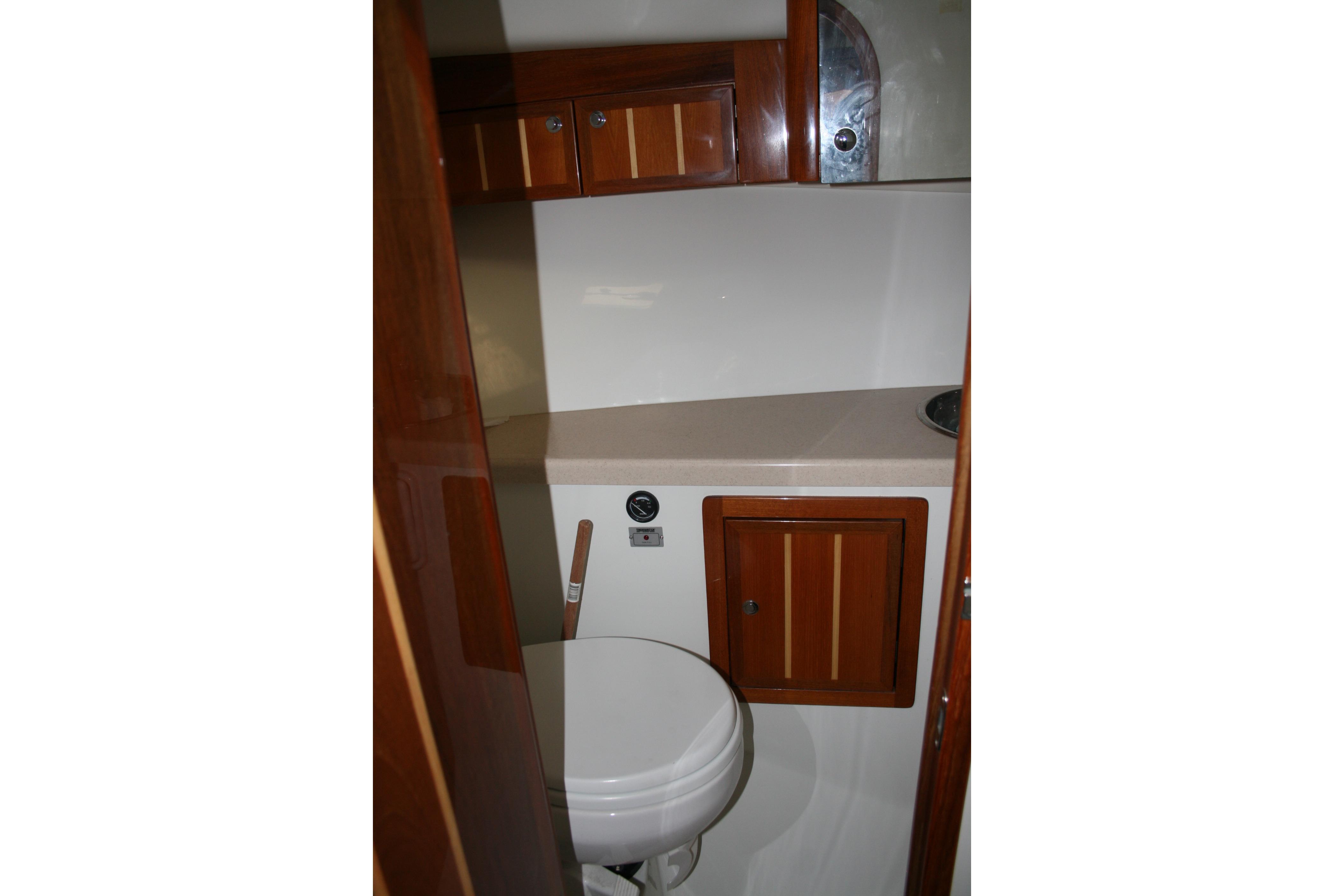 Compact bathroom in 2005 Ocean Sport 30' boat with wooden cabinetry and white fixtures.