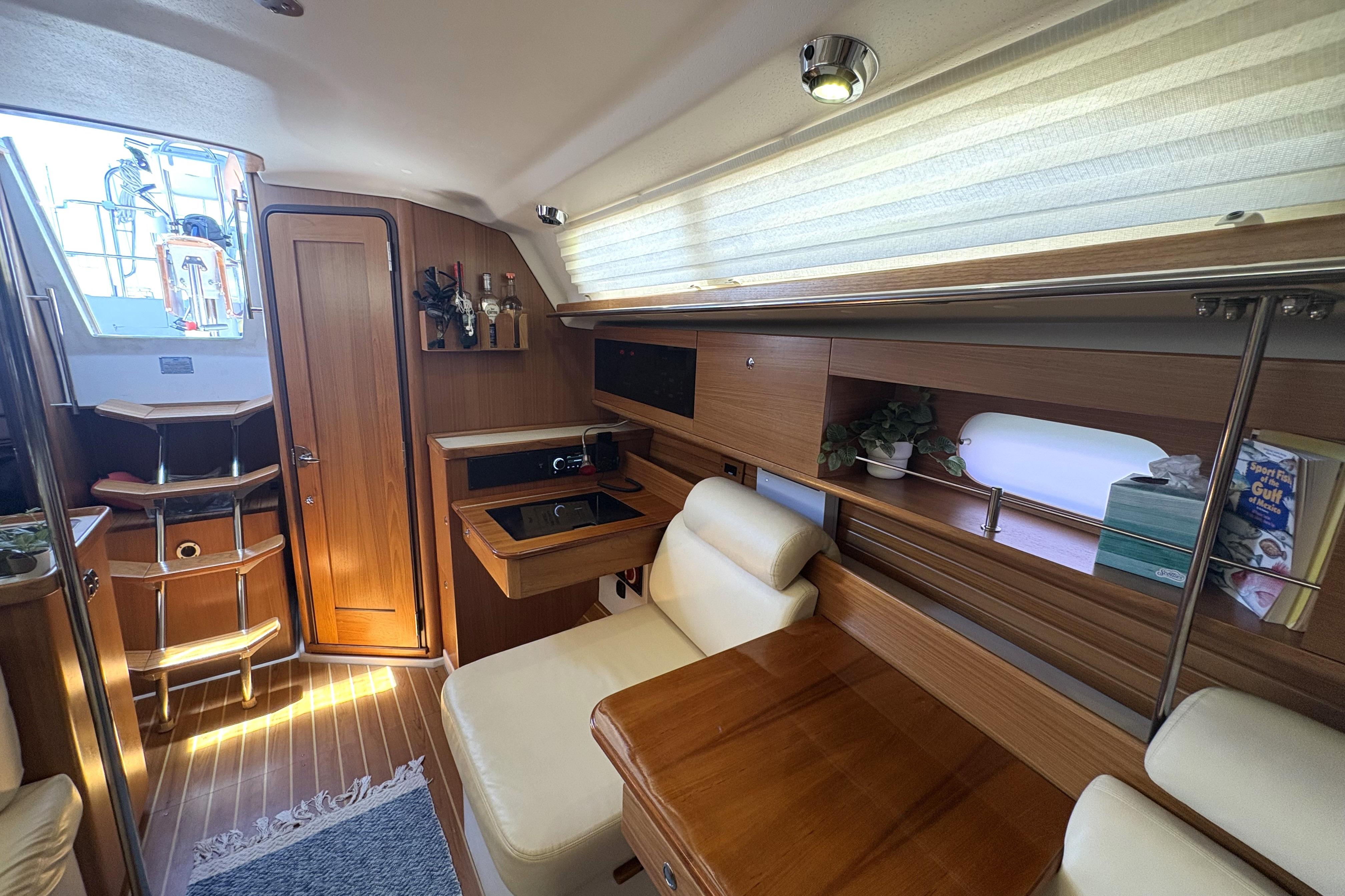 Interior of a 2011 Catalina 355 sailboat with cozy seating and wooden cabinetry.