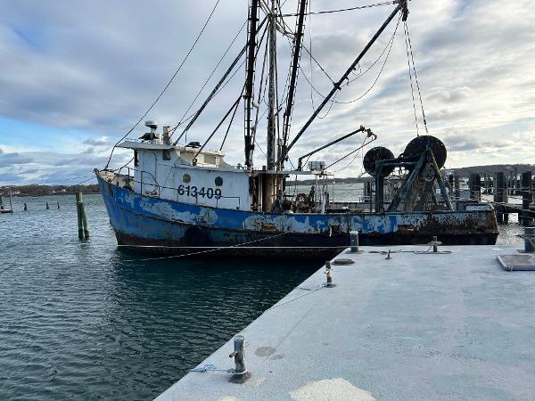 A 1979 Custom Steel Trawler Dragger docked at a marina under cloudy skies.