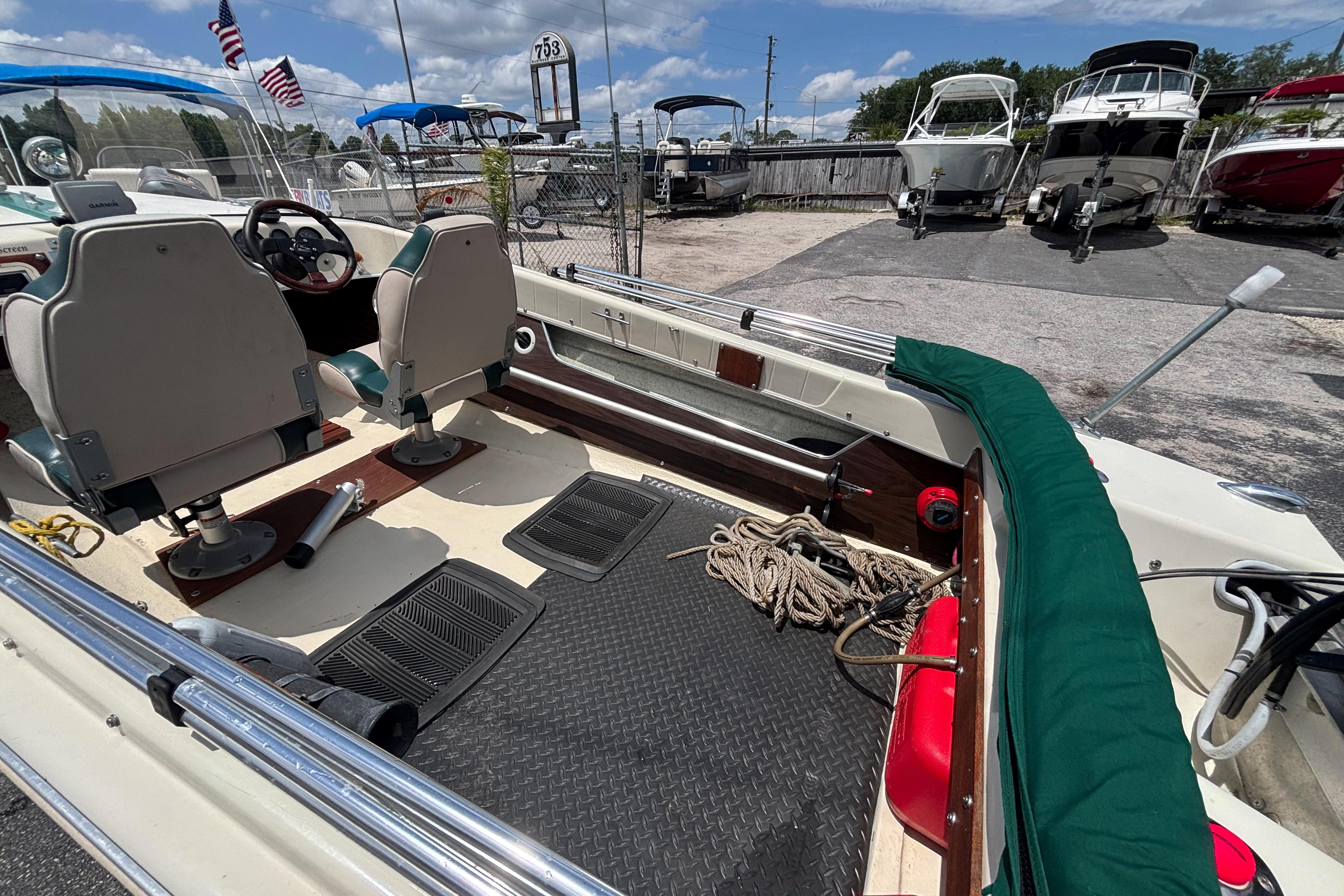 1966 Mohawk 15 boat interior with seats, steering wheel, and ropes, docked near other boats.