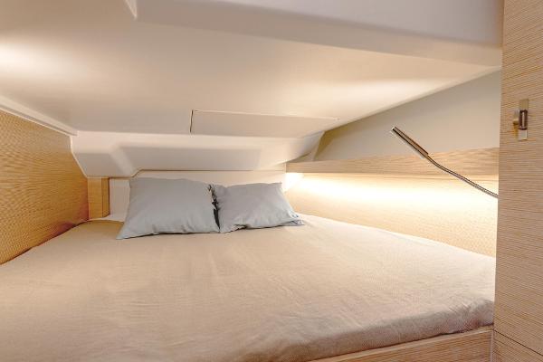 Cozy cabin interior of 2025 Hanse 360 yacht with modern bedding and ambient lighting.